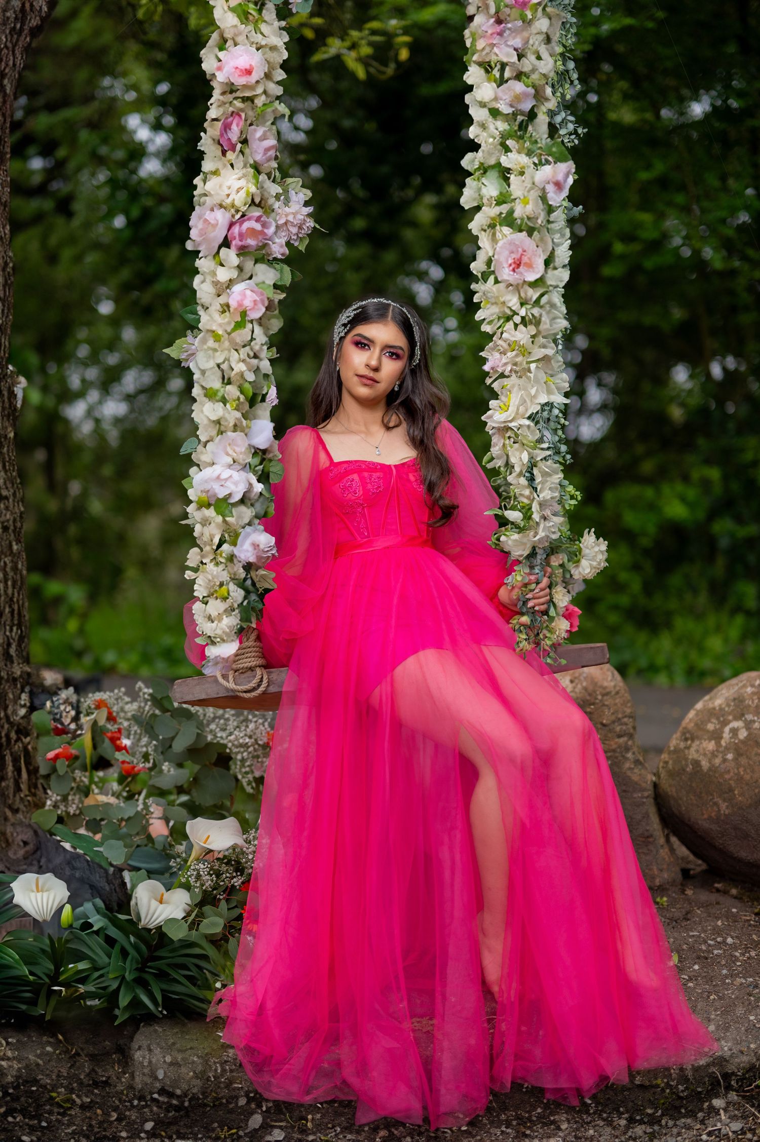 Modern quinceañera wearing hot pink tulle dress sitting on floral swing, outdoor session San Francisco