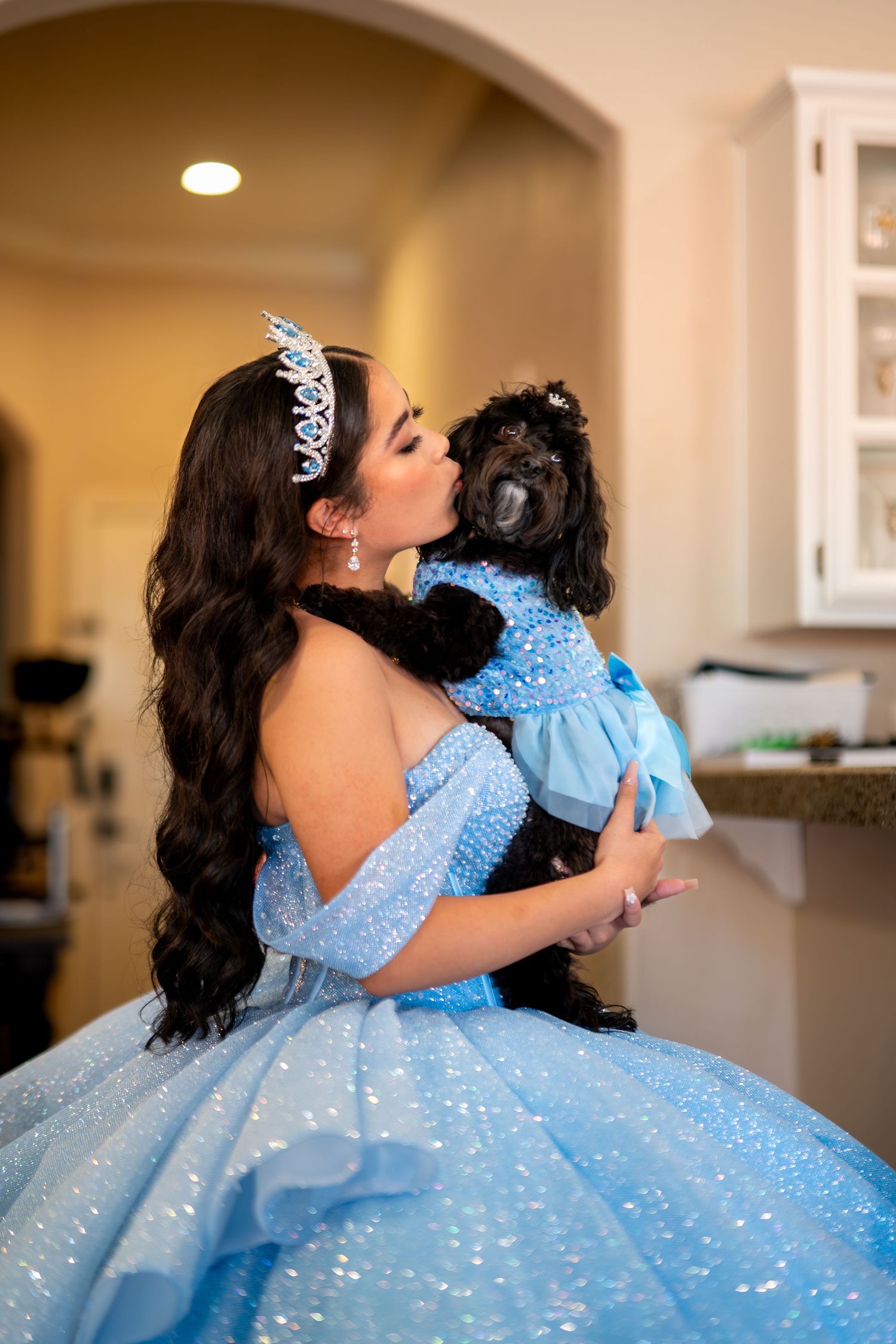 Quinceañera princess holding dog in matching blue dress during getting ready