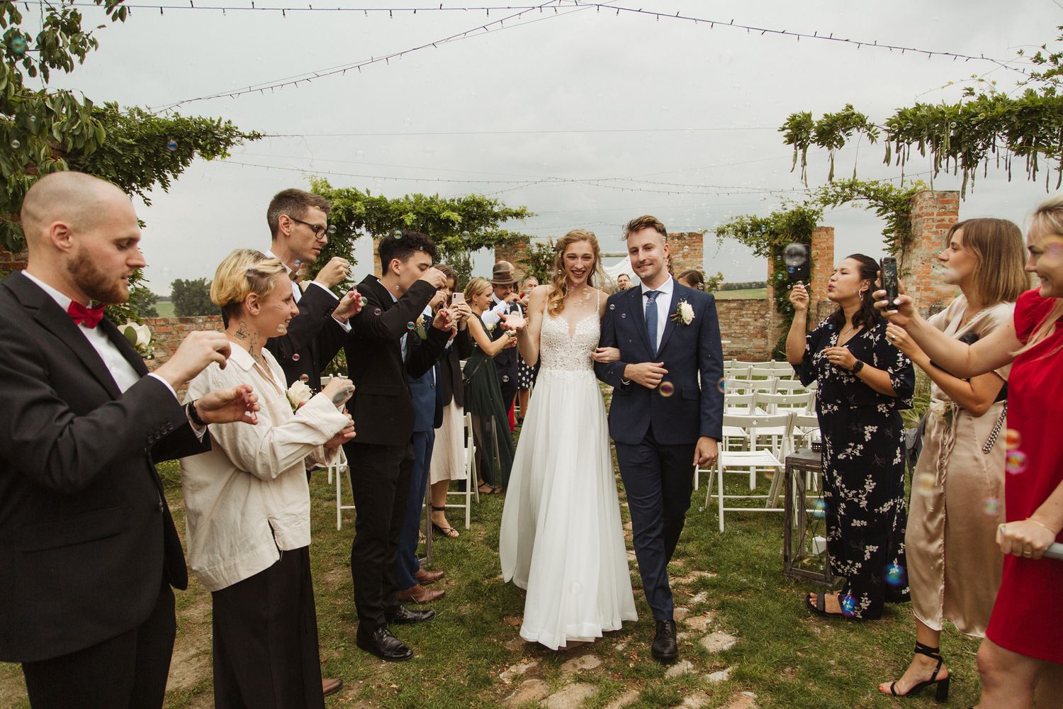 Wedding celebration on lawn with guests gathered around historic brick building.