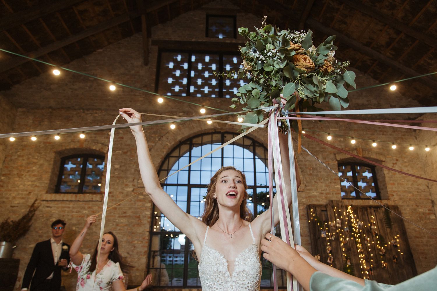 Wedding celebration moment in a brick venue with string lights and decorative greenery.