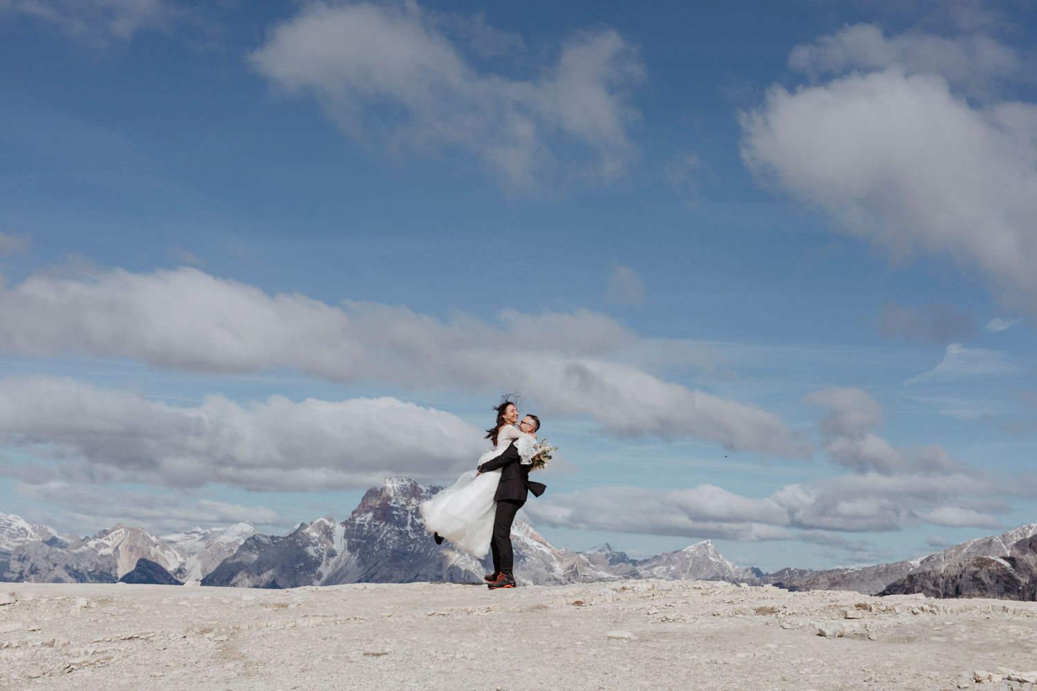 Panoramic view of snowy mountain landscape under blue sky with scattered clouds.
