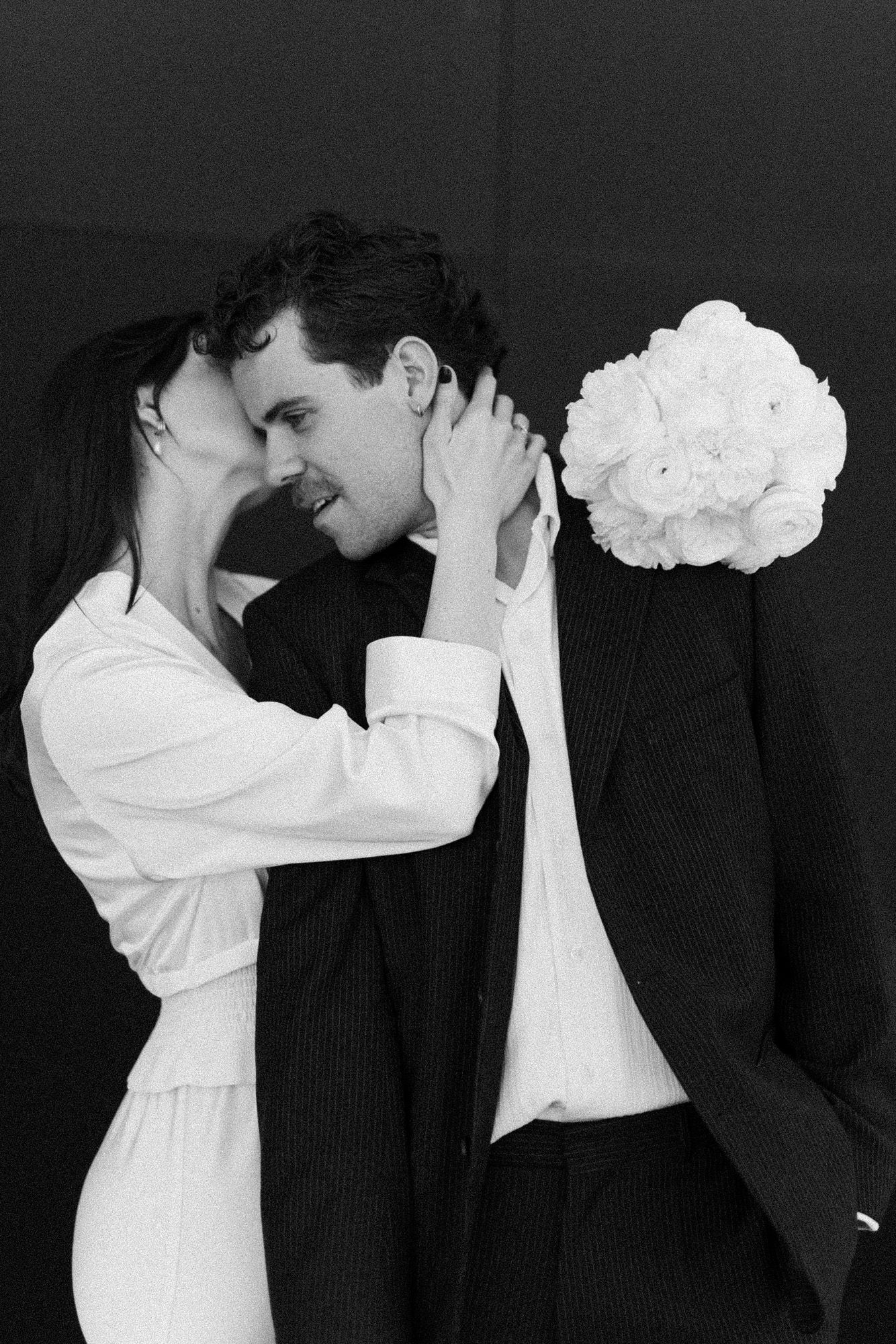 Black and white artistic wedding photos showing a sequence of intimate poses against dark backdrop.