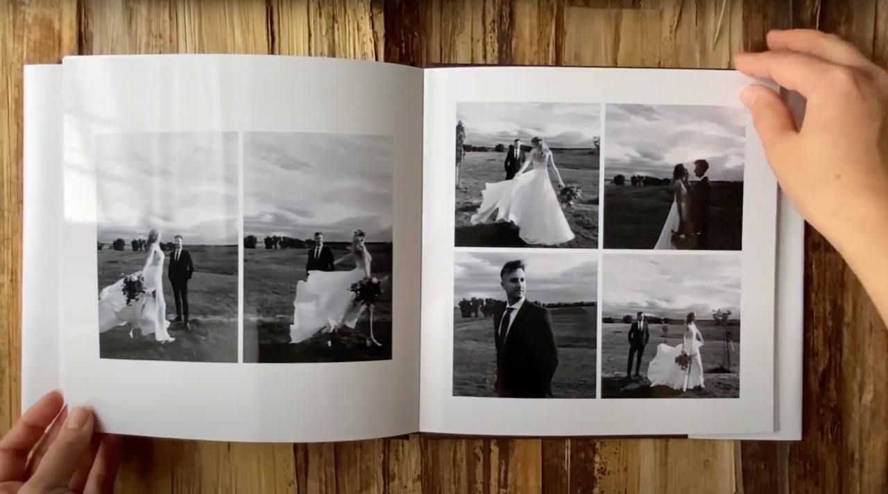 Black and white wedding photo album layout displayed on wooden surface.