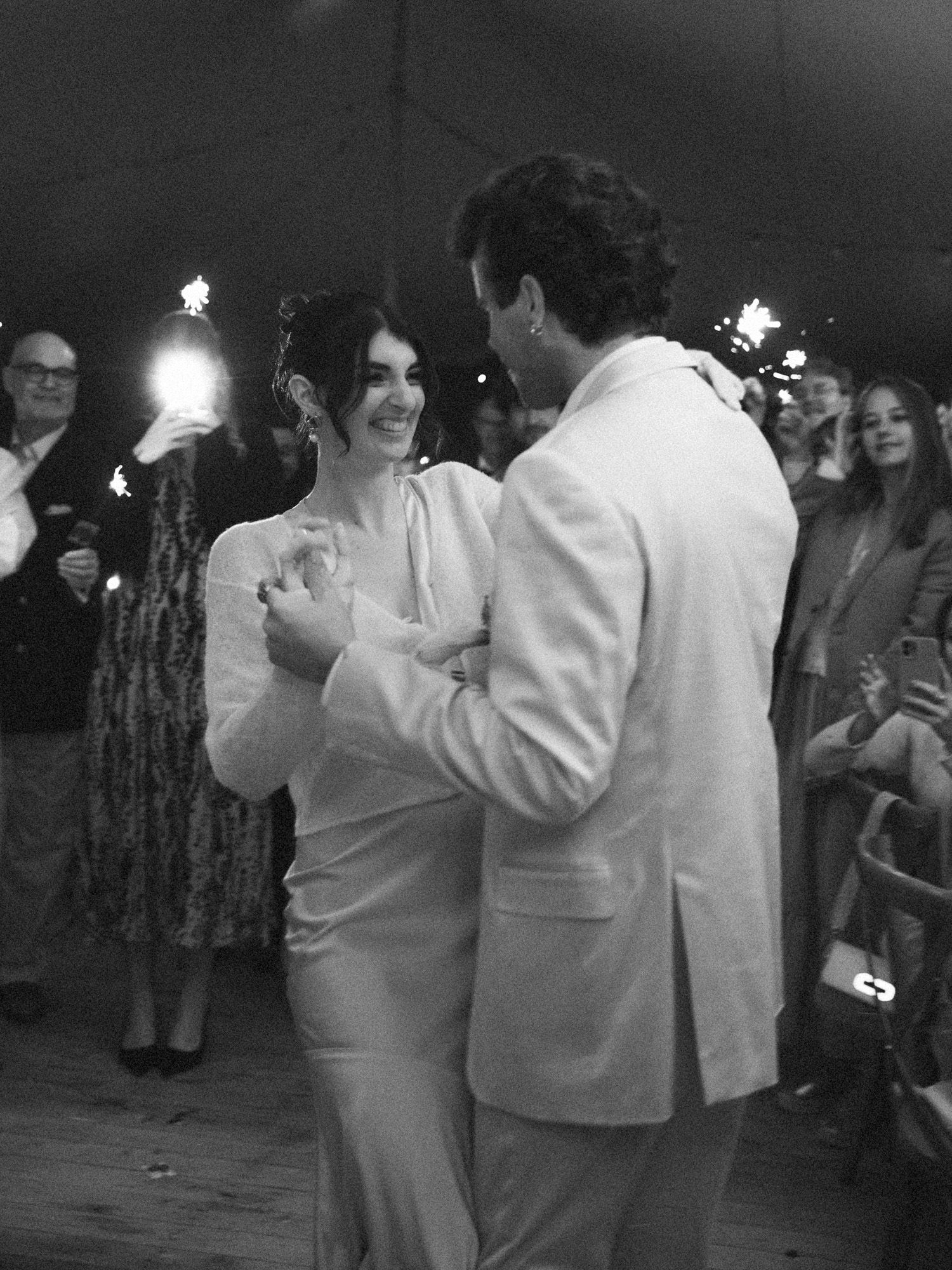 Black and white photo of wedding guests dancing at an evening reception.