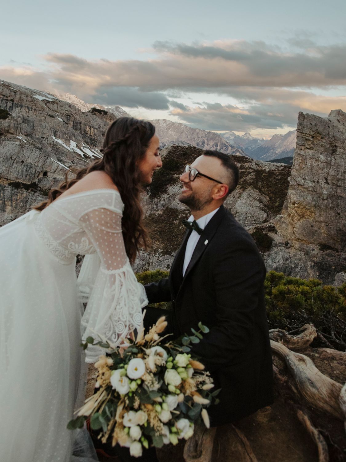 Intimate wedding moment captured against majestic mountain backdrop at sunset.
