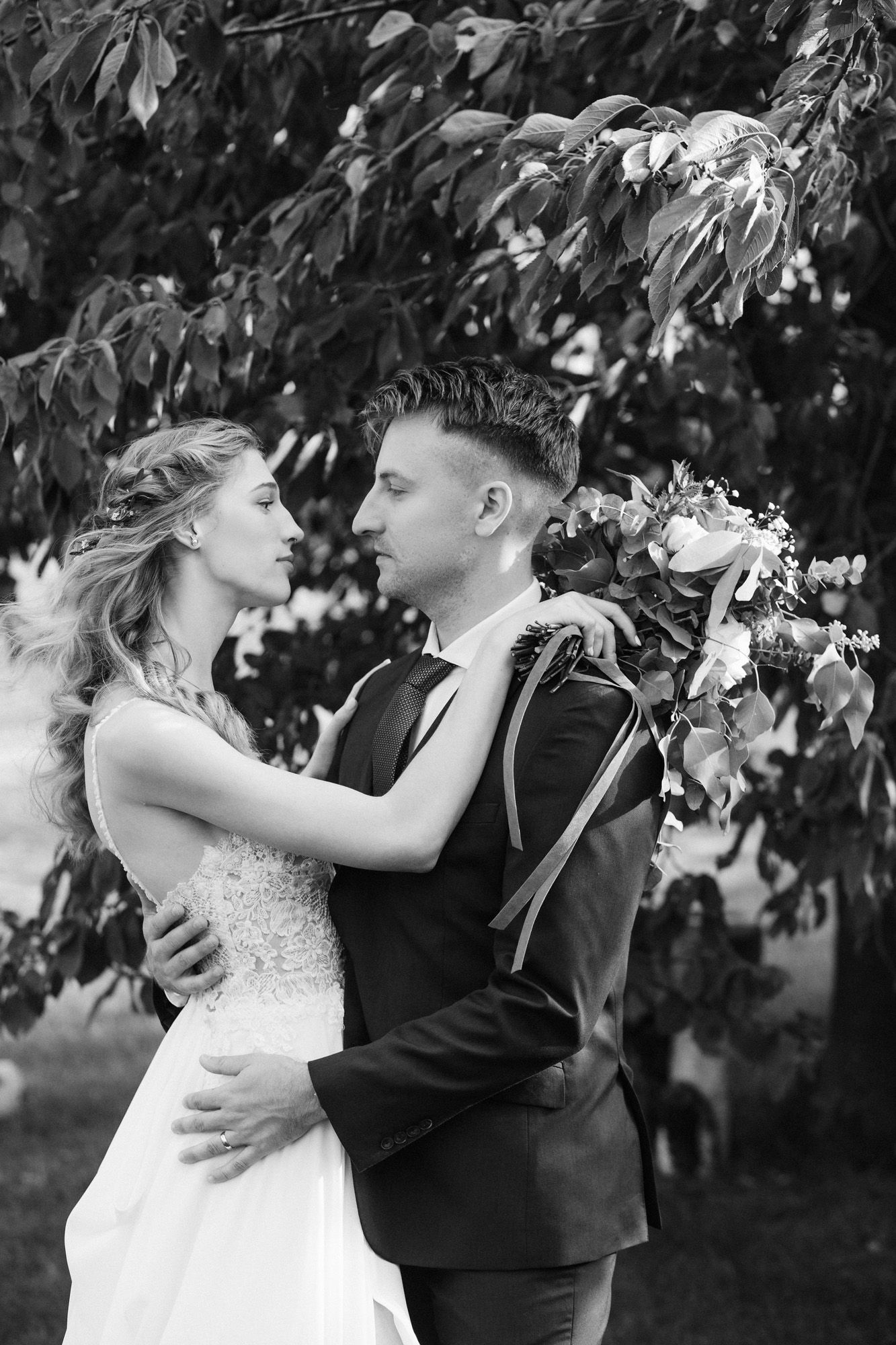Black and white romantic portrait under tree branches outdoors.