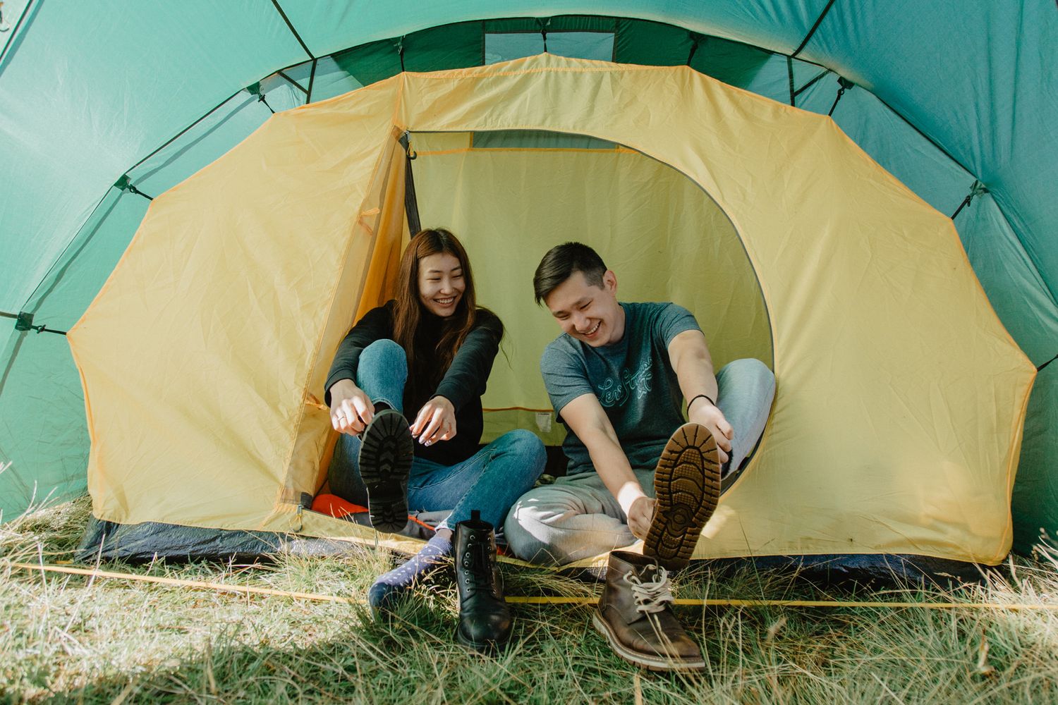 Inside view of yellow tent with people relaxing during camping trip.