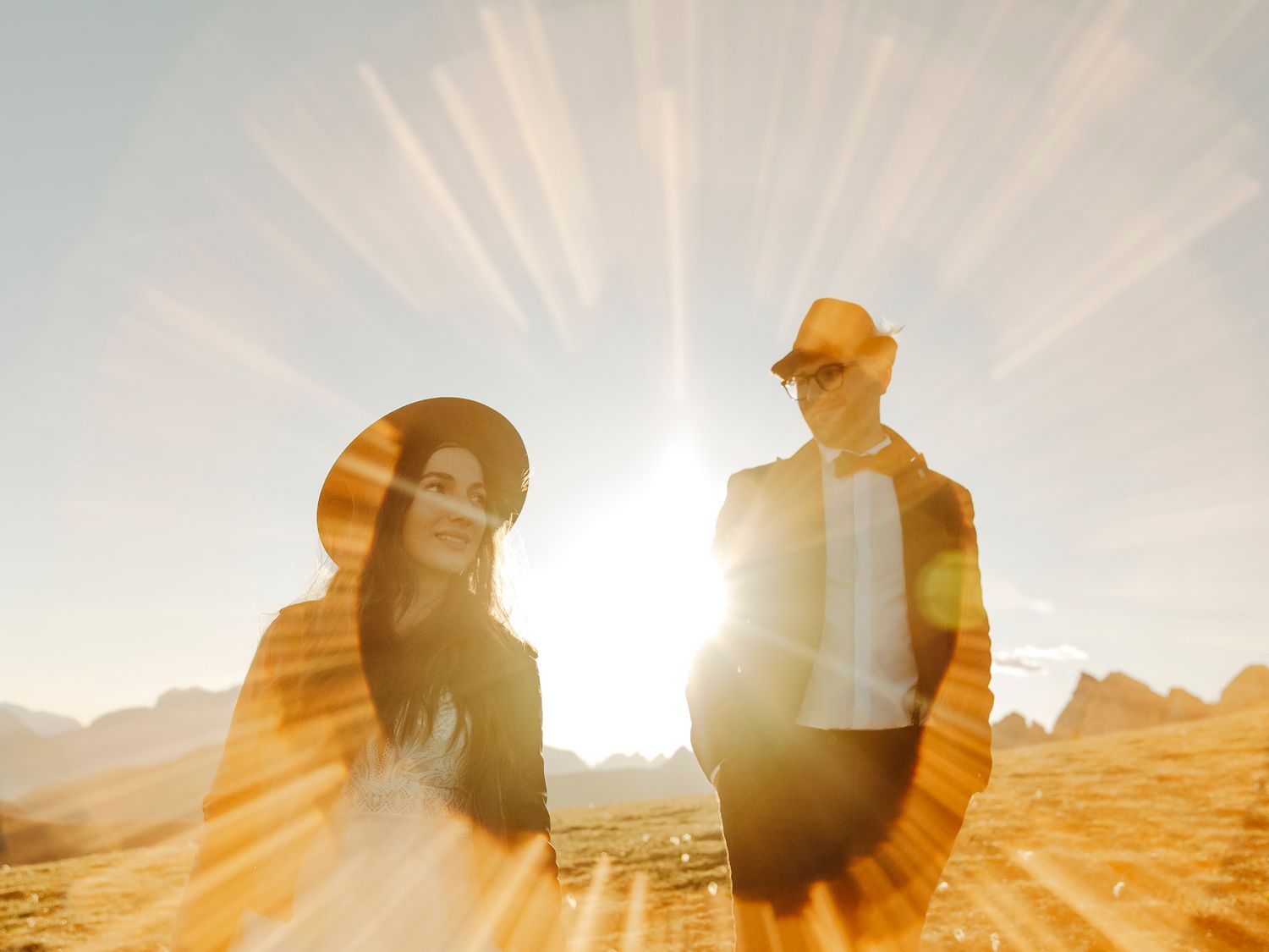 Silhouettes of people backlit by dramatic sunburst rays in desert landscape.