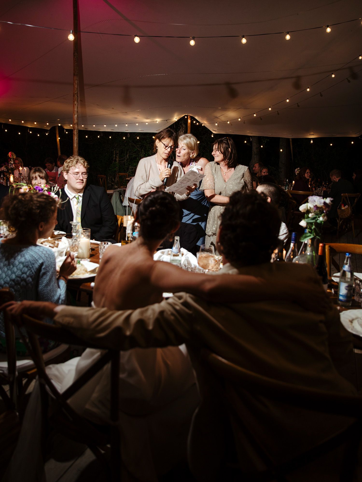 Wedding reception under a tent with string lights creating a warm ambient atmosphere.
