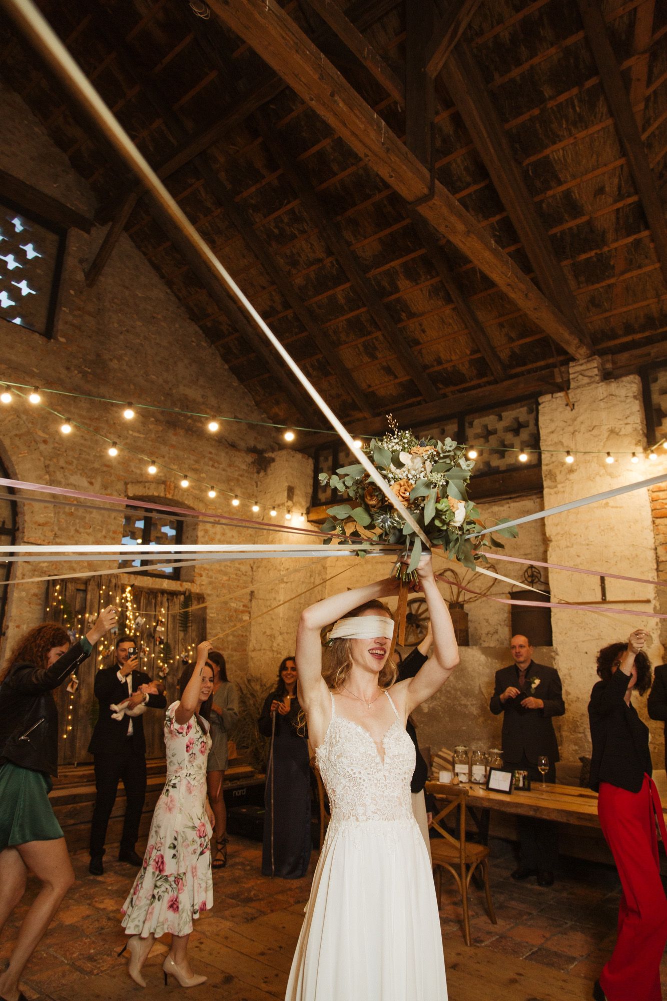 Wedding celebration with raised hands and decorative greenery in a rustic brick venue.