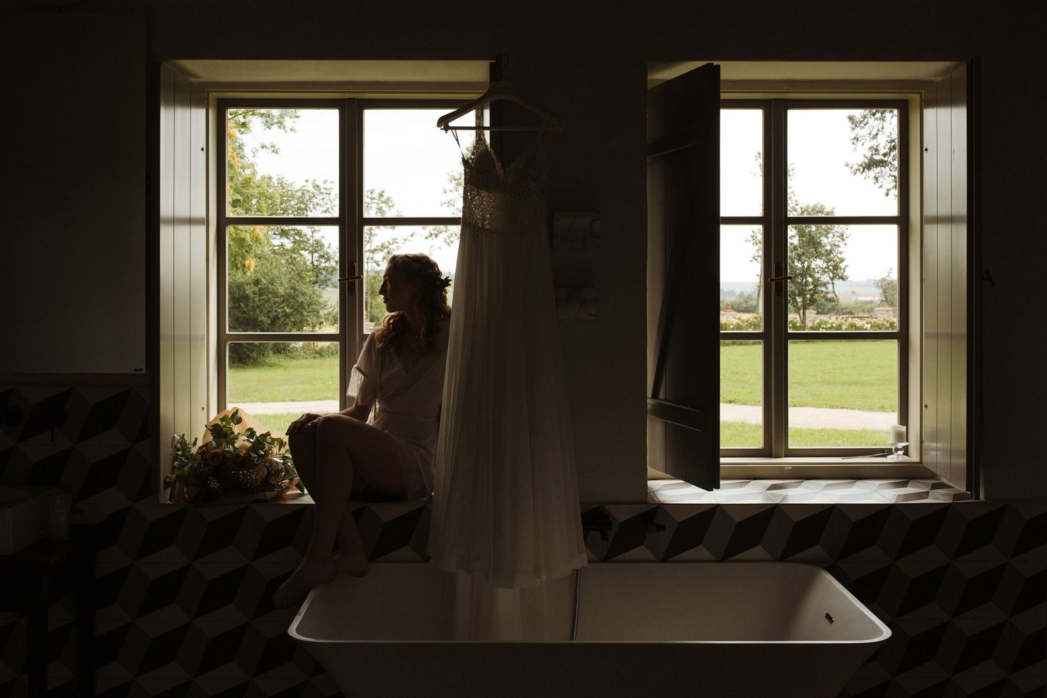 Dramatic window silhouette with wedding dress reflection in bathroom mirror.
