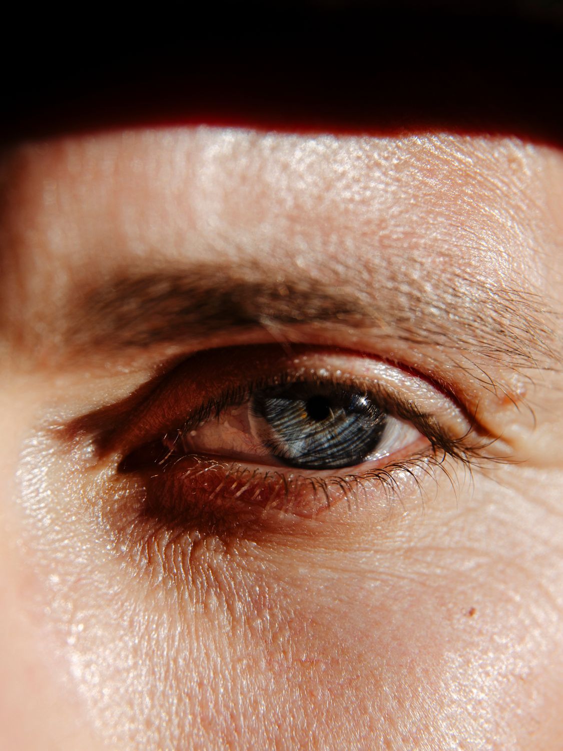 Extreme close-up of a blue eye with detailed texture and warm lighting.