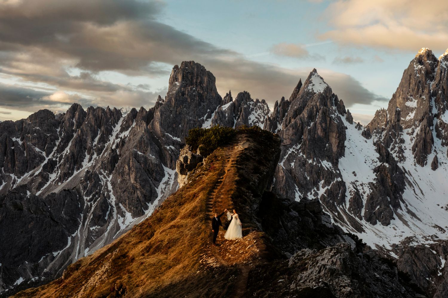 Epic mountain wedding photo on ridge trail in the Dolomites at sunset.