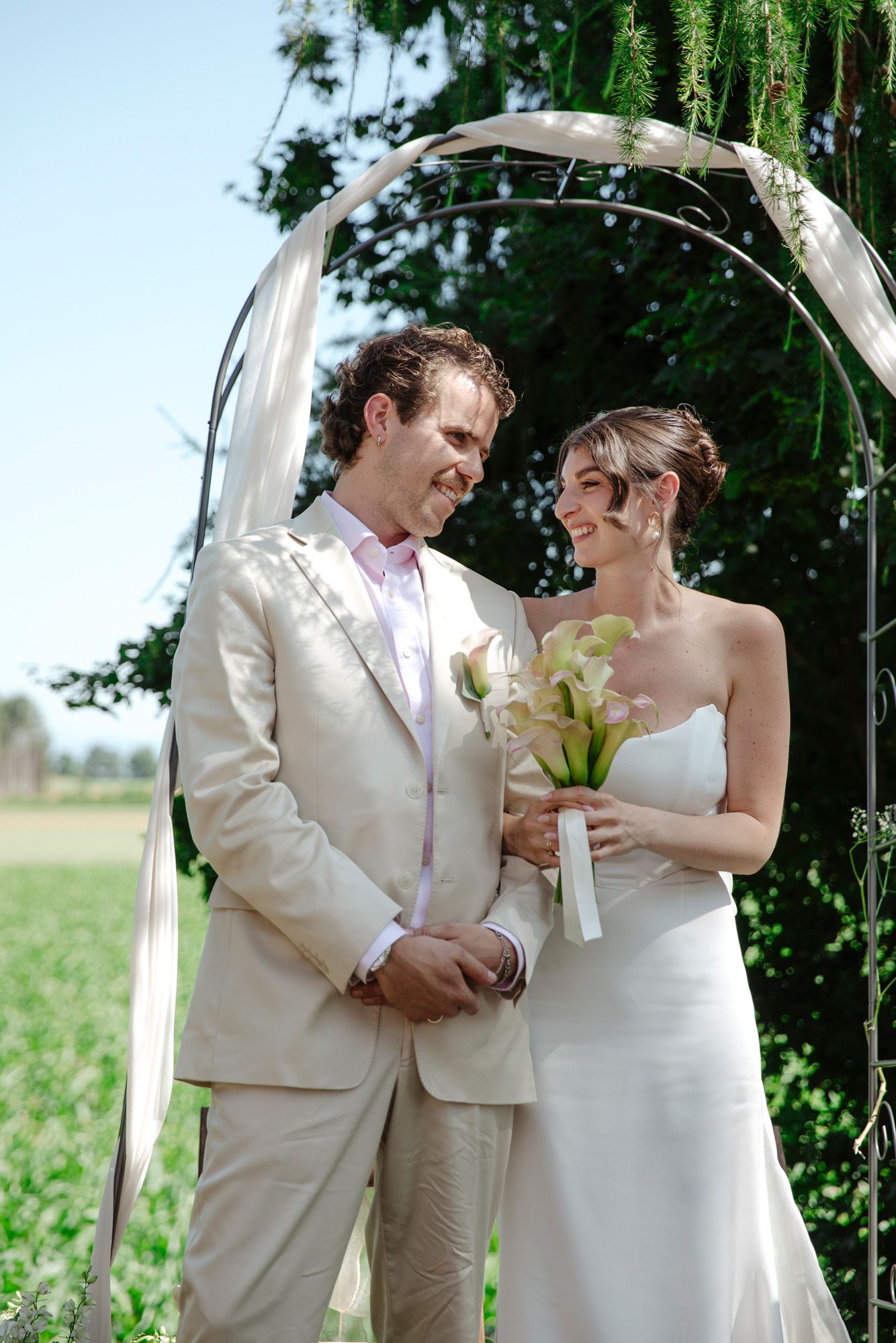 Elegant summer wedding ceremony under a willow tree with white floral bouquet.
