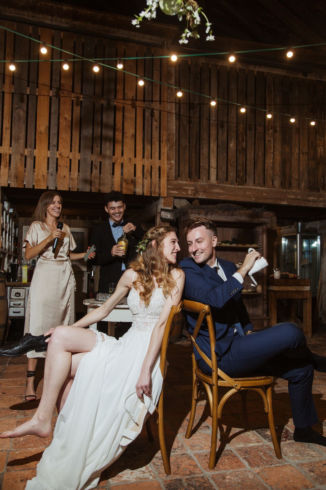 Reception celebration in a rustic barn venue with string lights and wooden details.