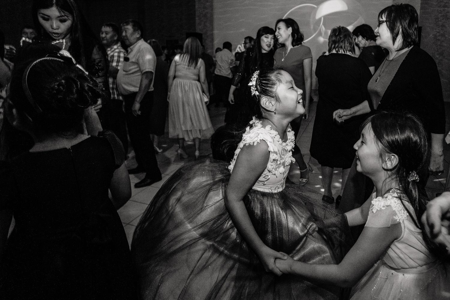 Black and white photo capturing joyful dancing at wedding reception.