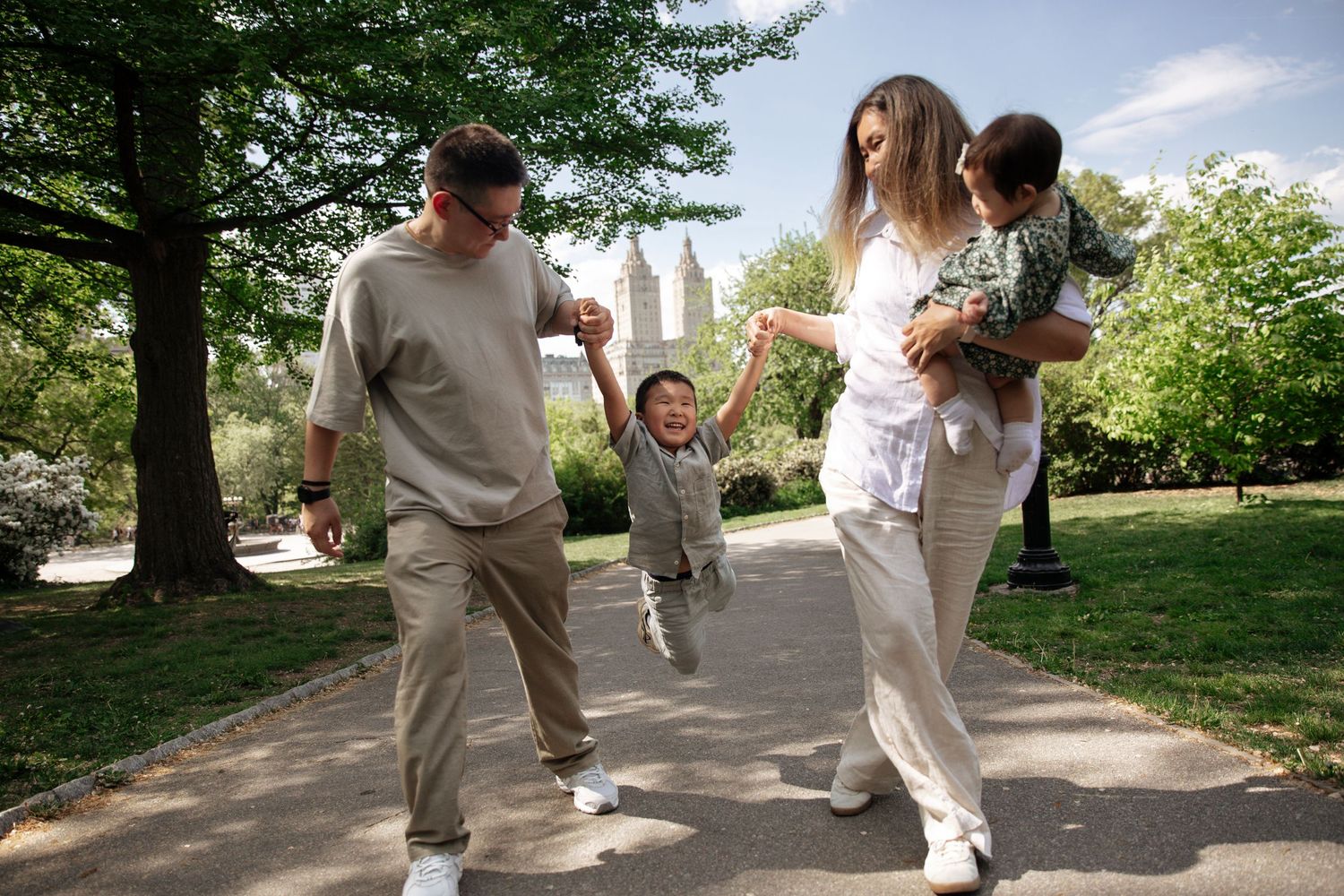 A couple in white outfits dancing and jumping joyfully in a garden path.