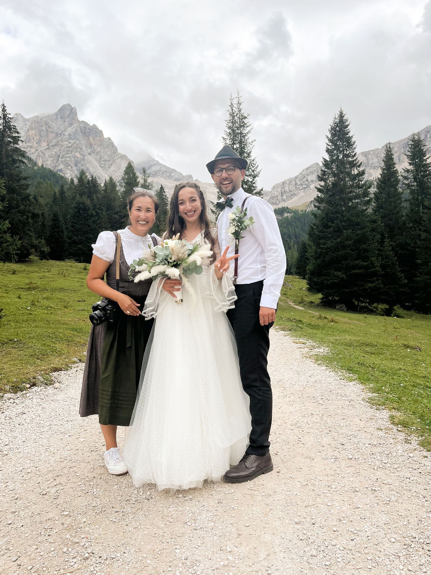 Wedding party poses on mountain trail with dramatic Dolomites peaks in background.
