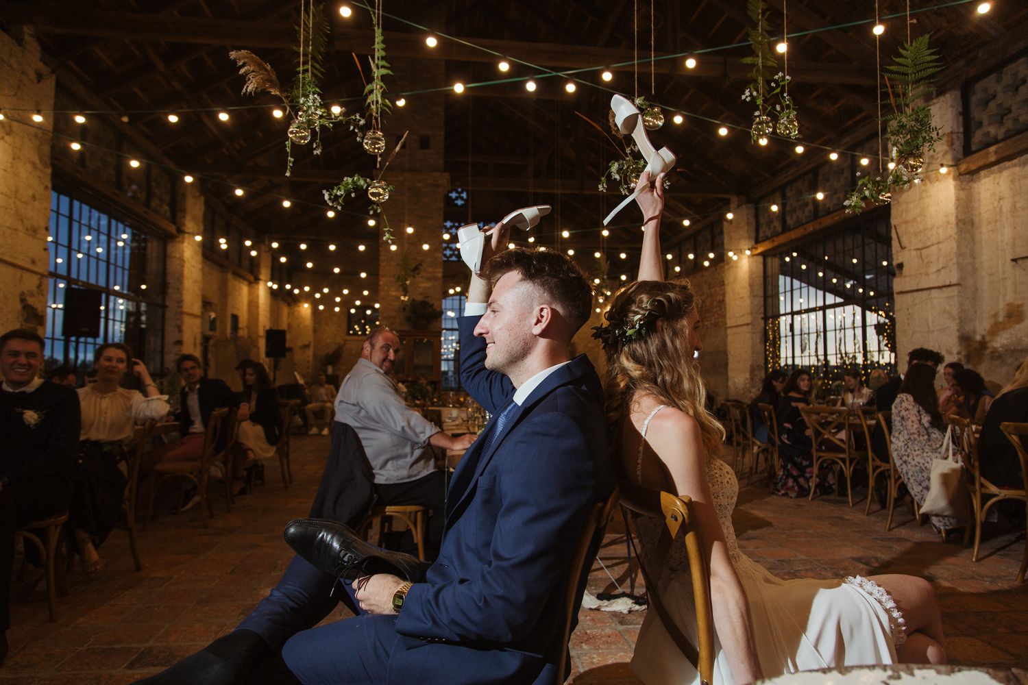 A wedding reception scene in a rustic venue with string lights overhead creating a warm ambiance.
