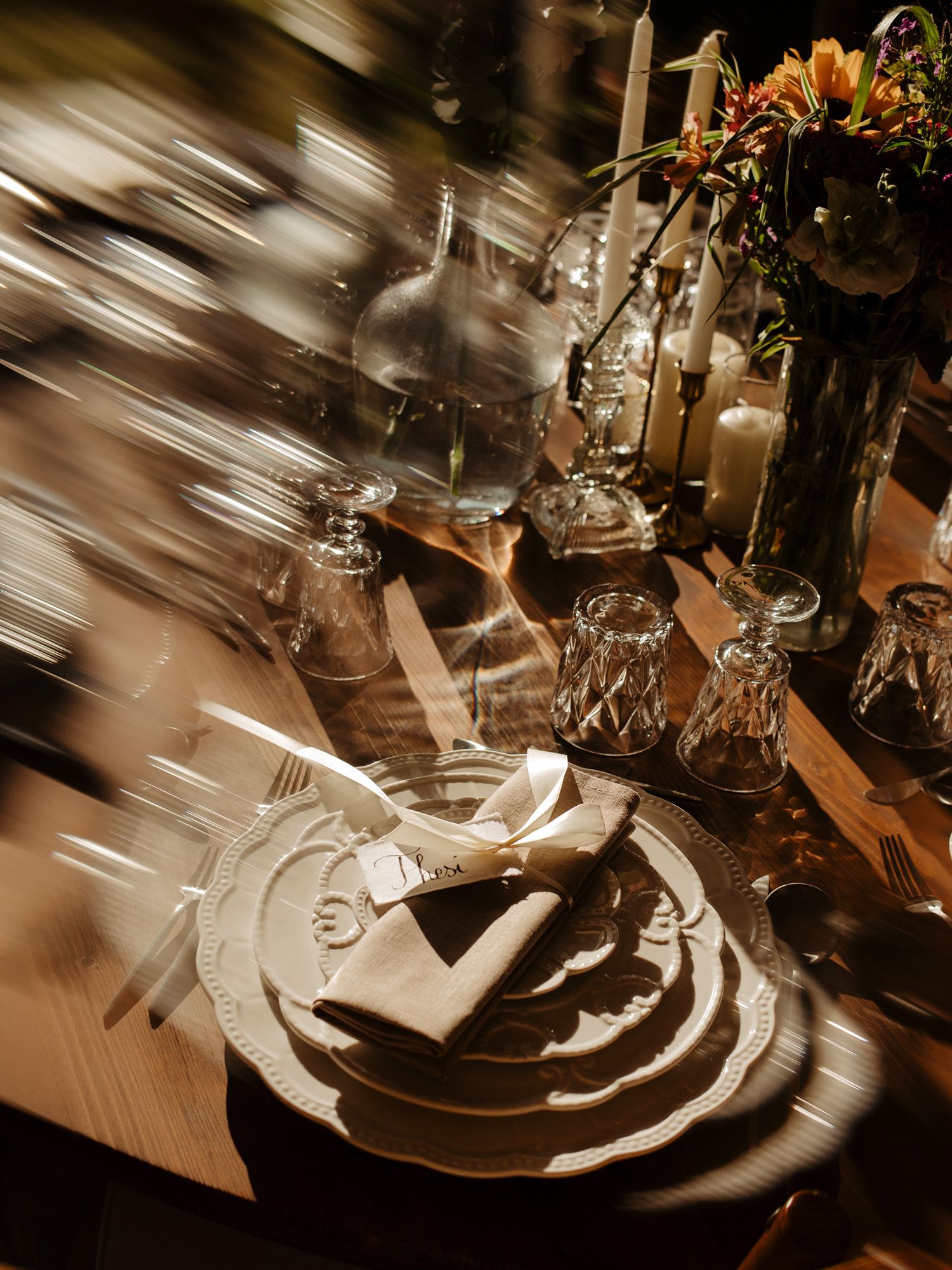 Close-up of an elegant table setting with wine glasses and candles in warm lighting.