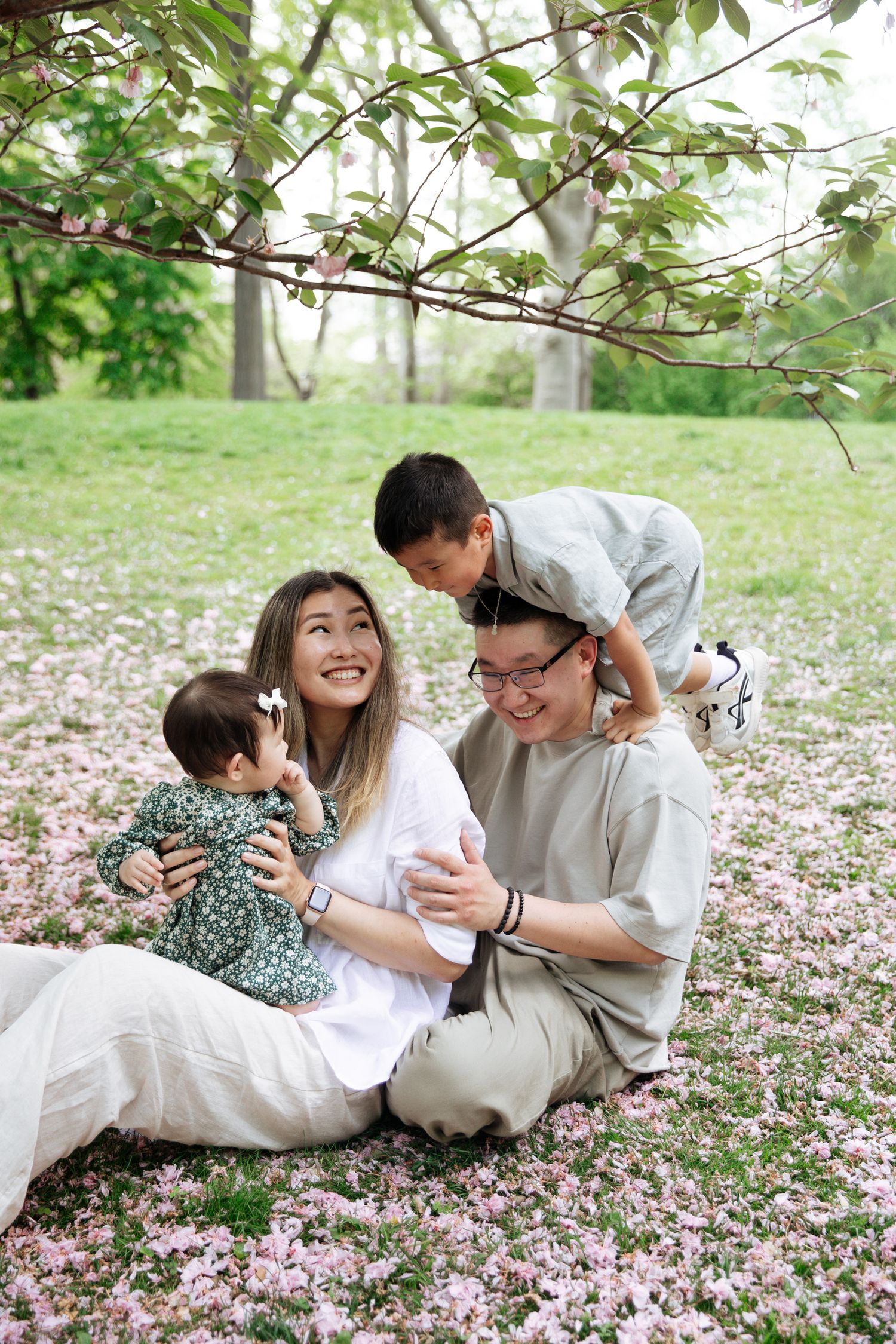 Laughing couple enjoying a photo session in a garden with pink flowers on the ground.