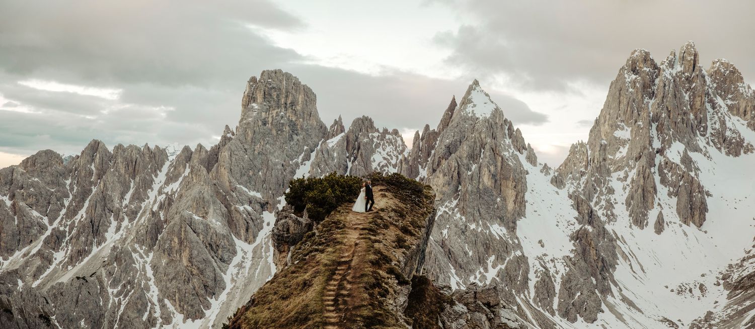Panoramic mountain landscape with snow-covered peaks under cloudy skies.