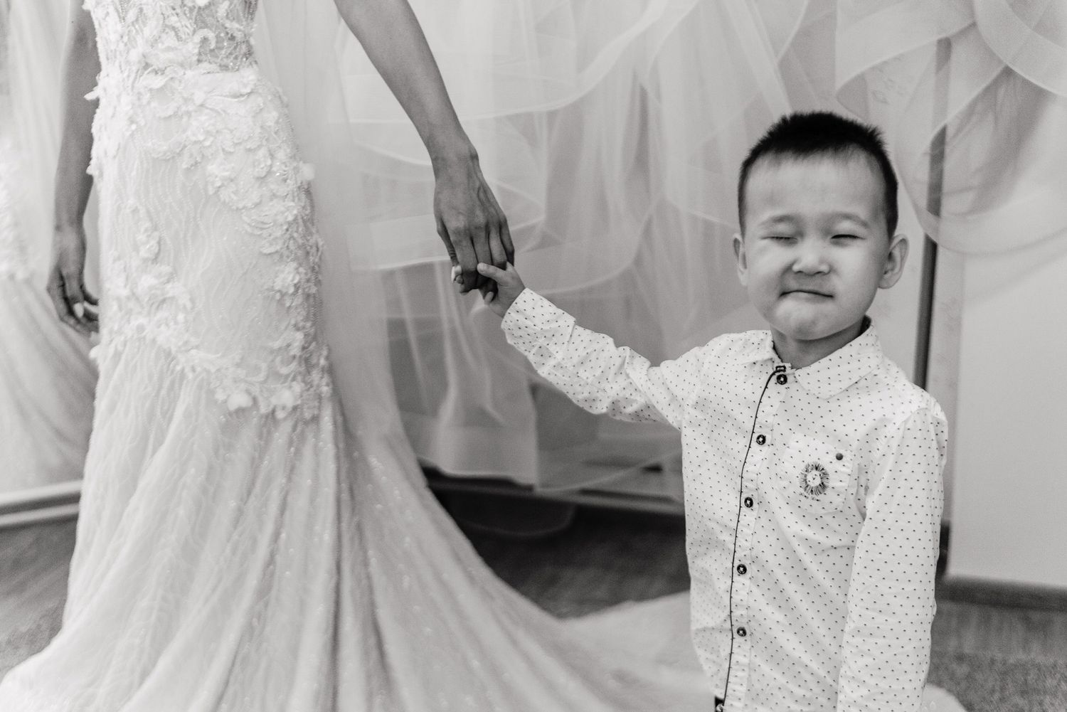 An intimate black and white photo showing details of delicate white lace wedding attire.