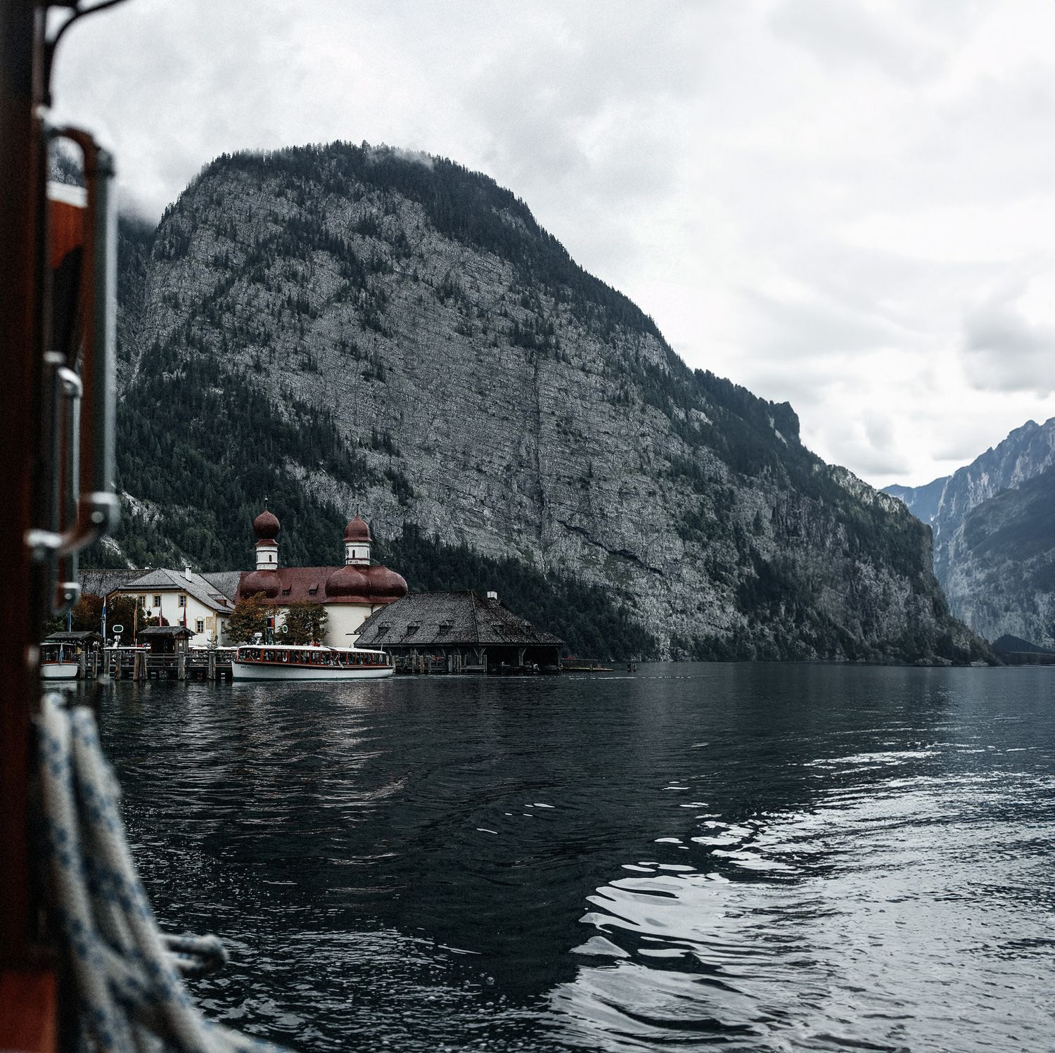 Dark mountain lake surrounded by steep cliffs and scattered buildings along the shoreline.