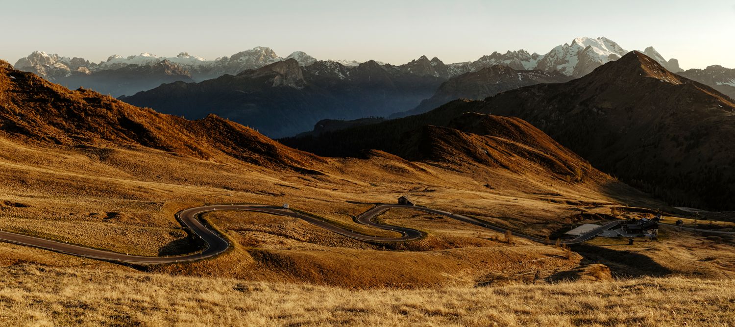 Panoramic view of golden mountain slopes with snow-capped peaks in distance.