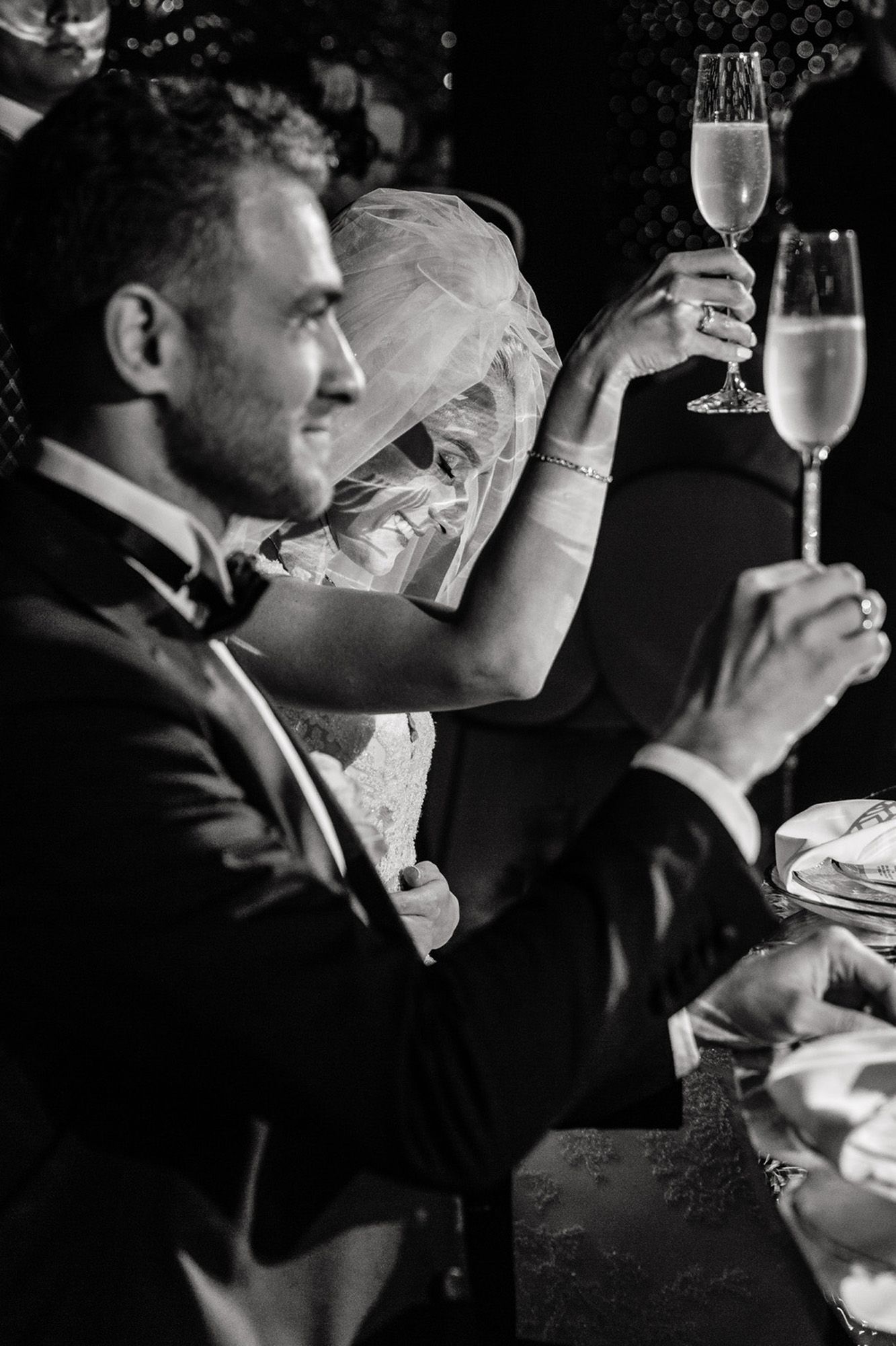 Black and white photo series showing a couple in formal attire toasting with champagne glasses at an elegant event.