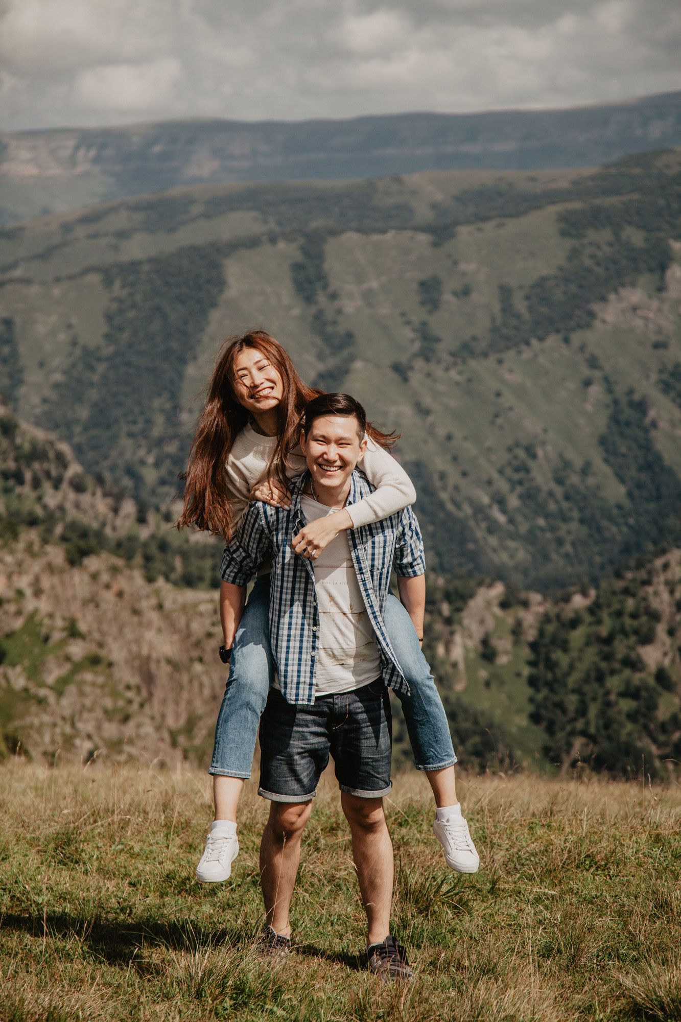 Two people enjoying a playful piggyback ride moment in the mountains.