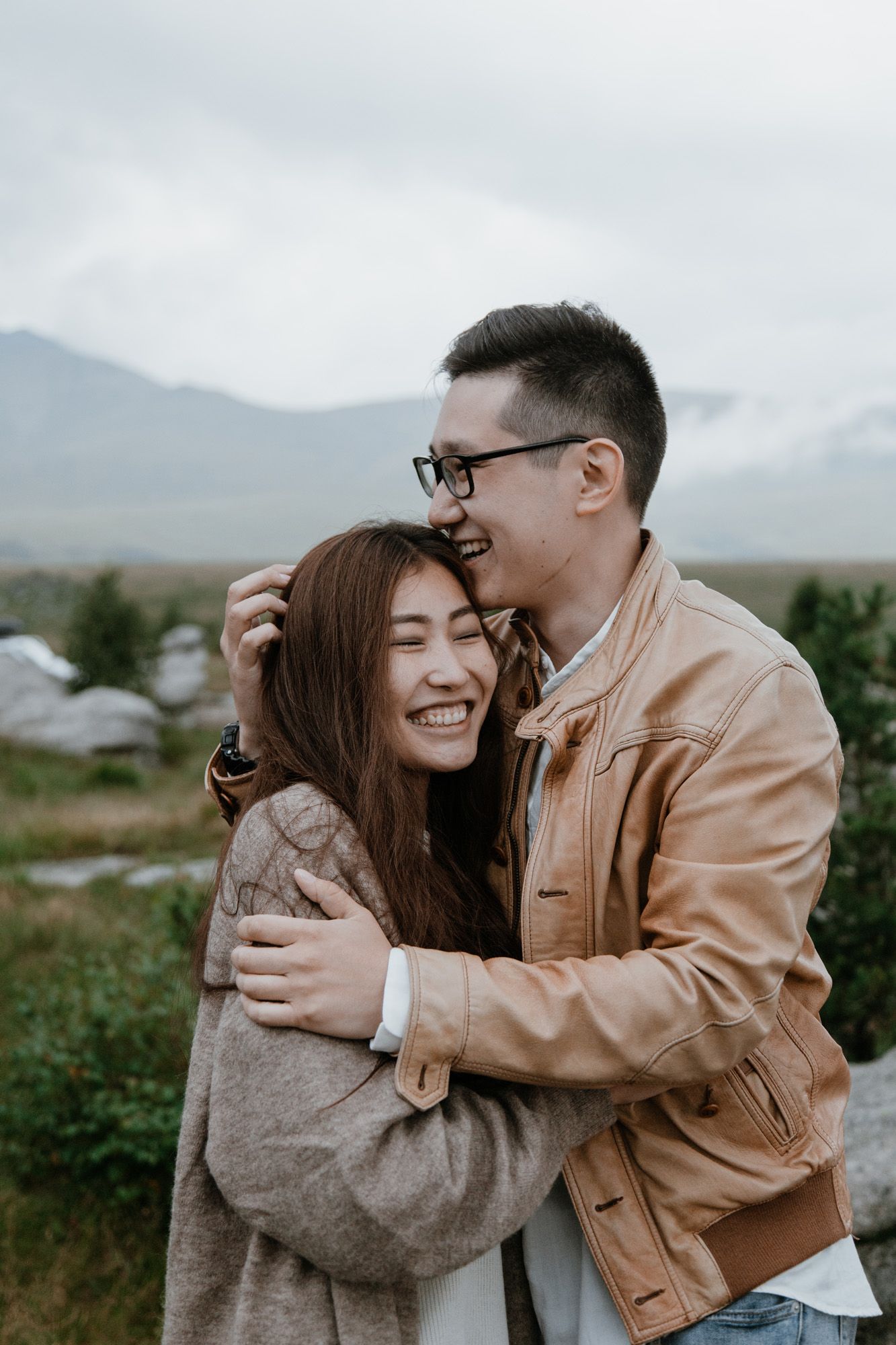 A tender moment shared between two people against a misty mountain backdrop.