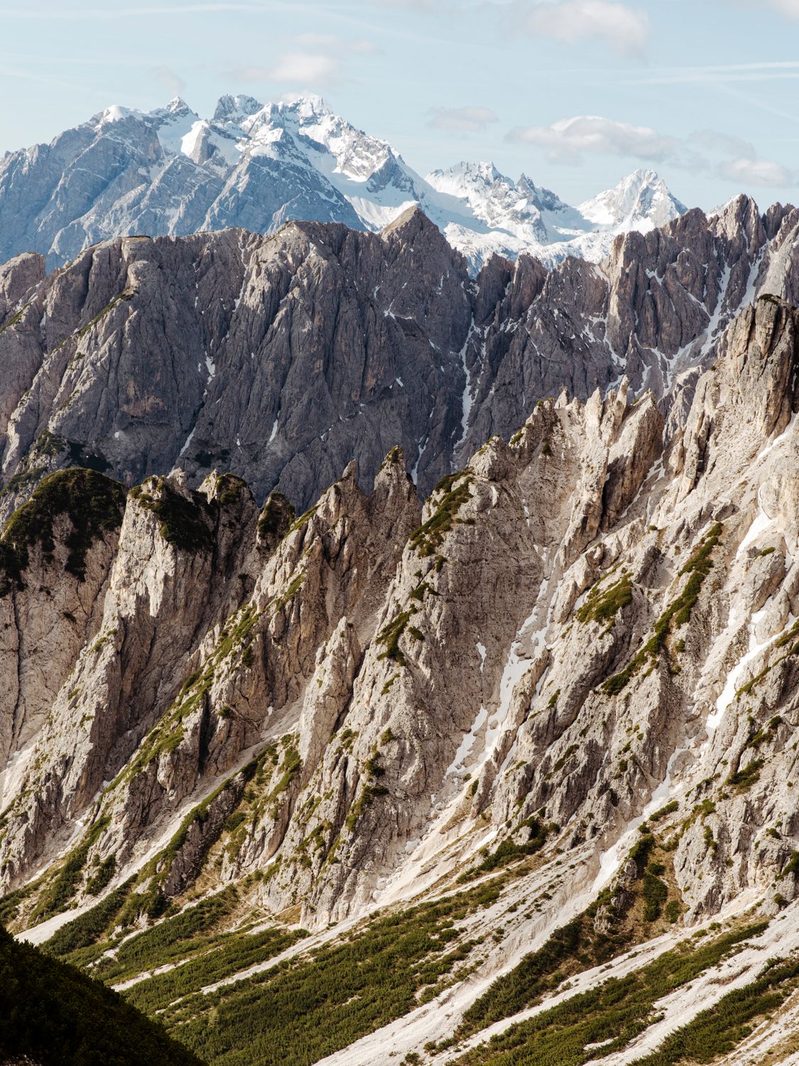 Majestic jagged cliffs of the Dolomites mountains rise against a clear blue sky.