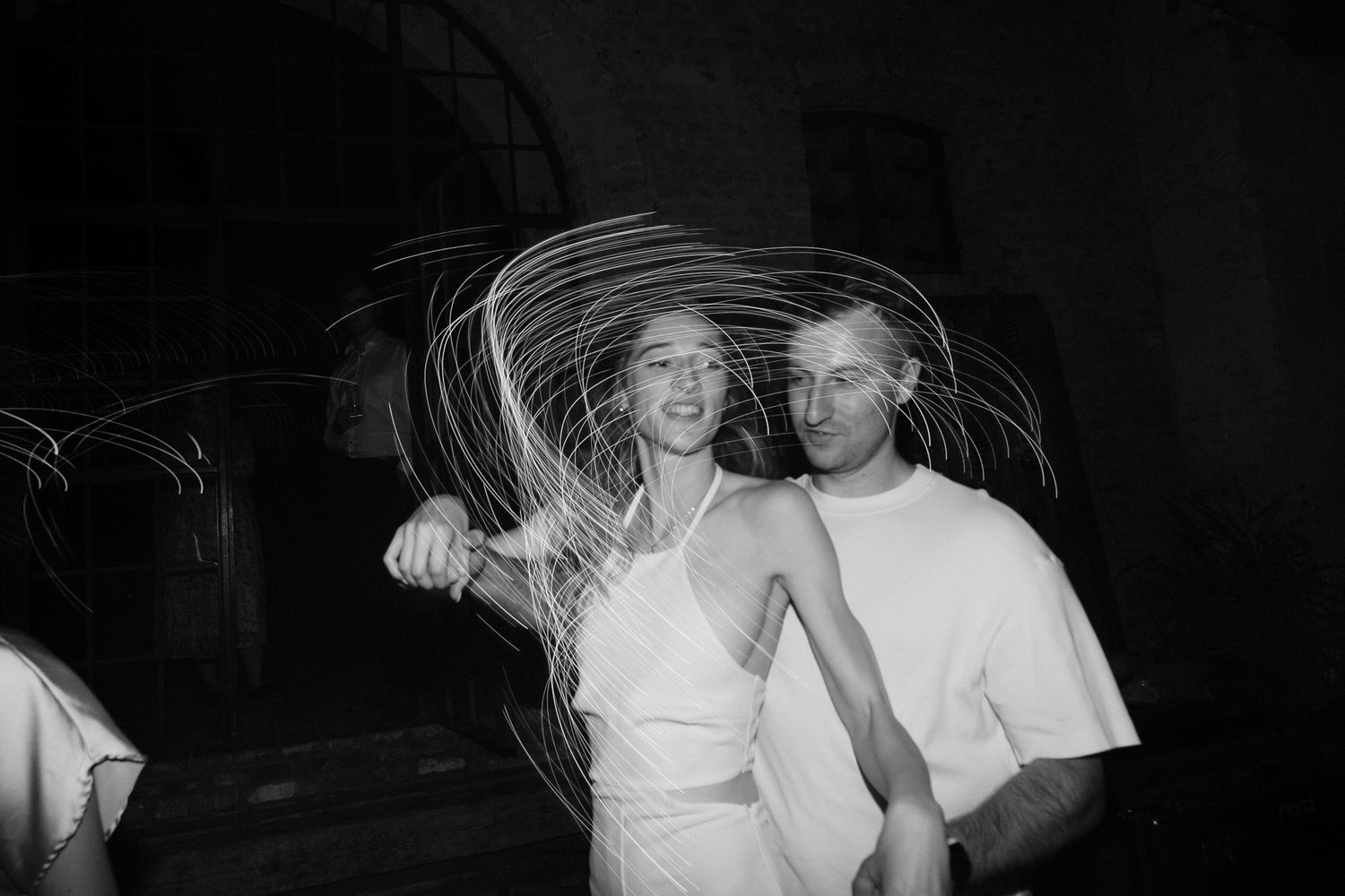 Black and white photo of dancers with light trails creating circular patterns around them.