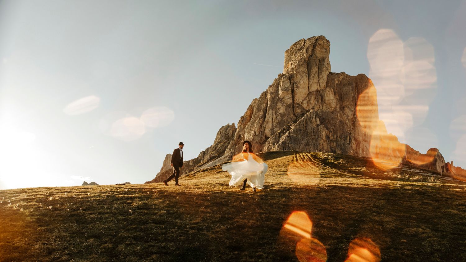Rocky mountain peak silhouetted against a golden sunset sky with lens flare.