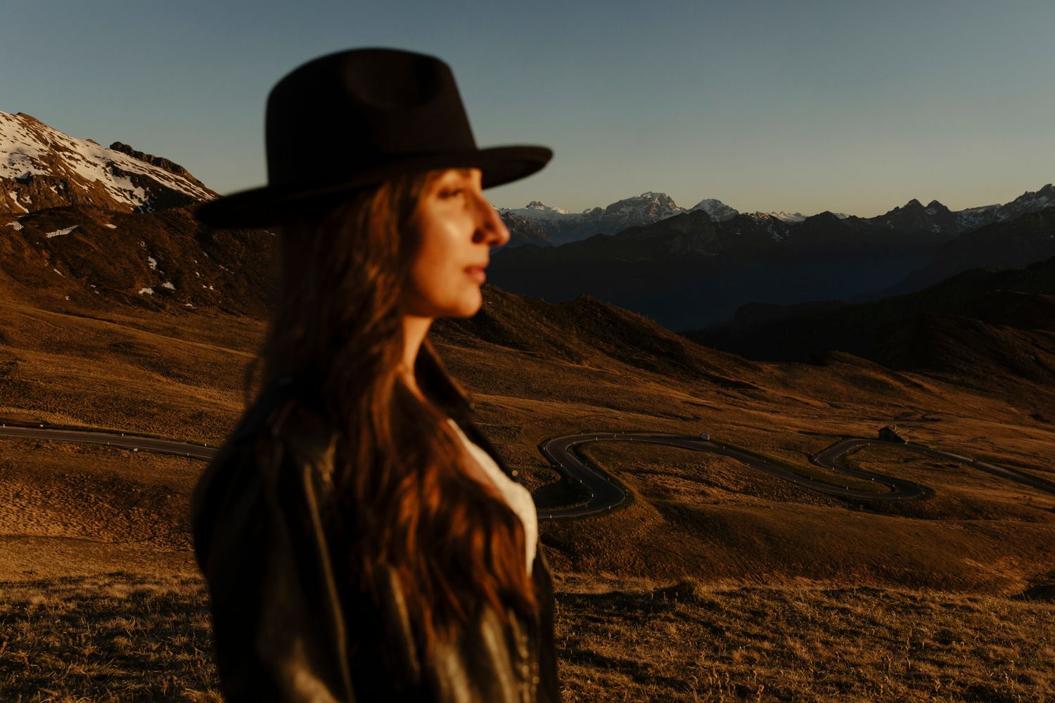 Silhouette of a person in a hat against mountainous landscape at sunset.