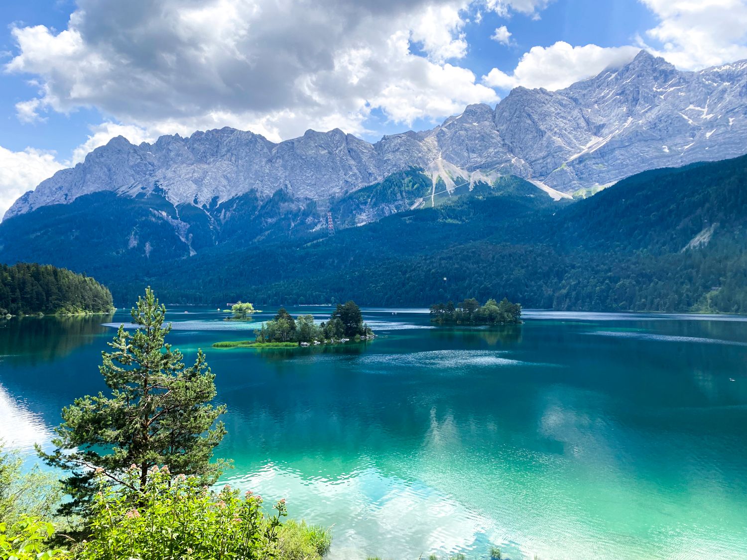 Stunning turquoise alpine lake surrounded by majestic mountain peaks under a blue summer sky.