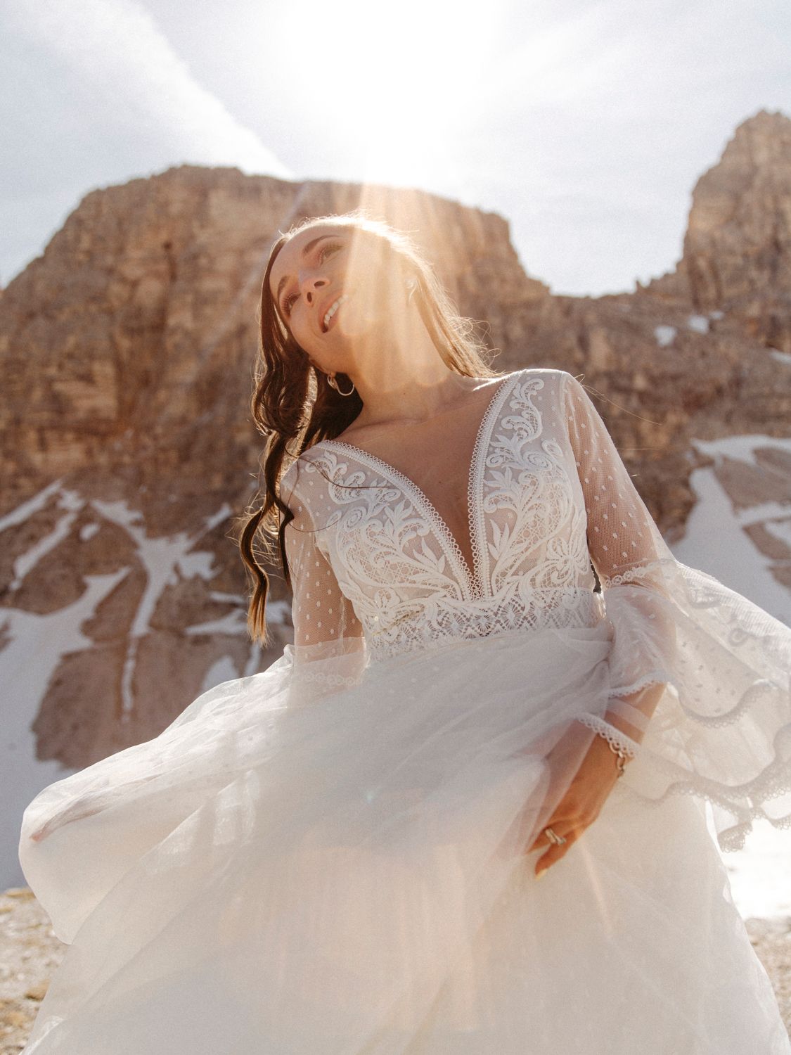 Close-up details of lace wedding dress with mountains visible in background.