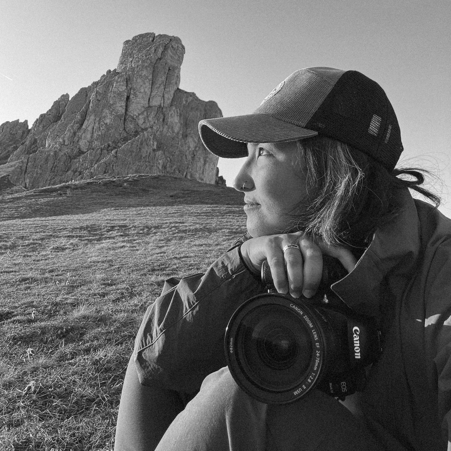 Photographer with camera gazing at dramatic mountain landscape in black and white.