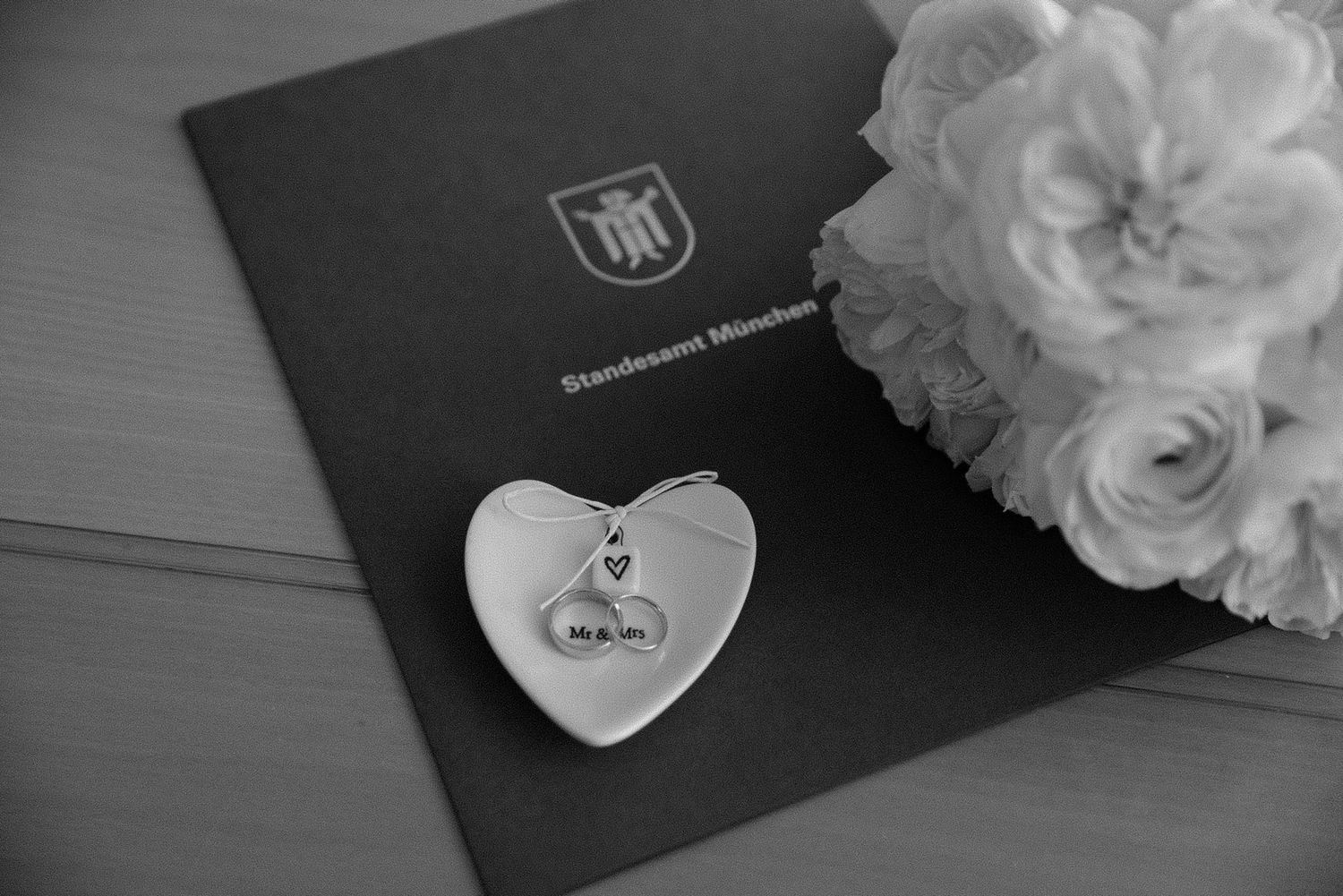 Wedding details featuring elegant white roses and invitation cards in monochrome.
