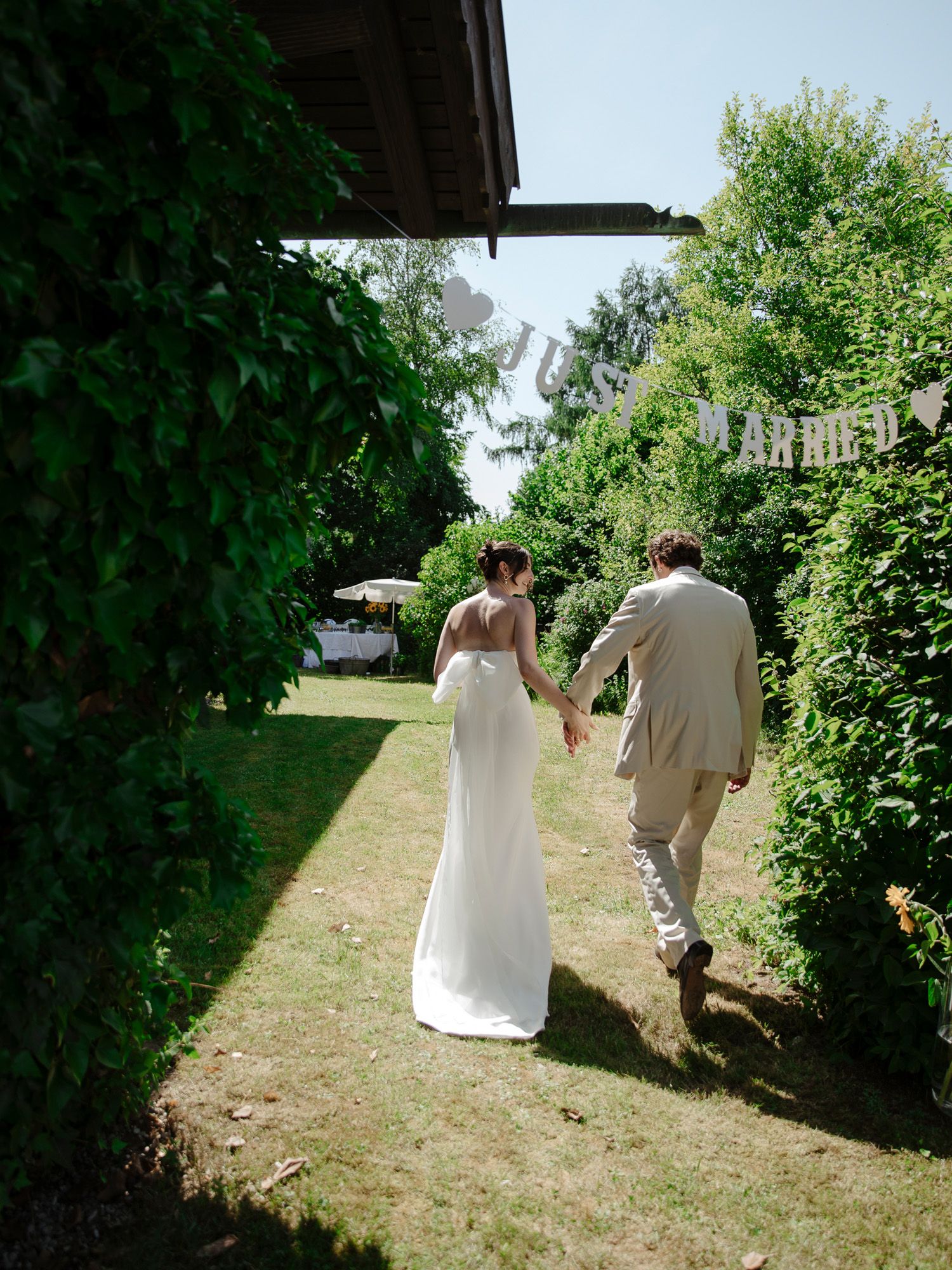 Newlyweds walking away down a green garden path after their ceremony.