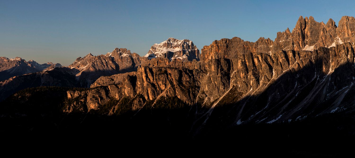 Dramatic mountain range silhouetted against clear sky at dusk in the Dolomites.
