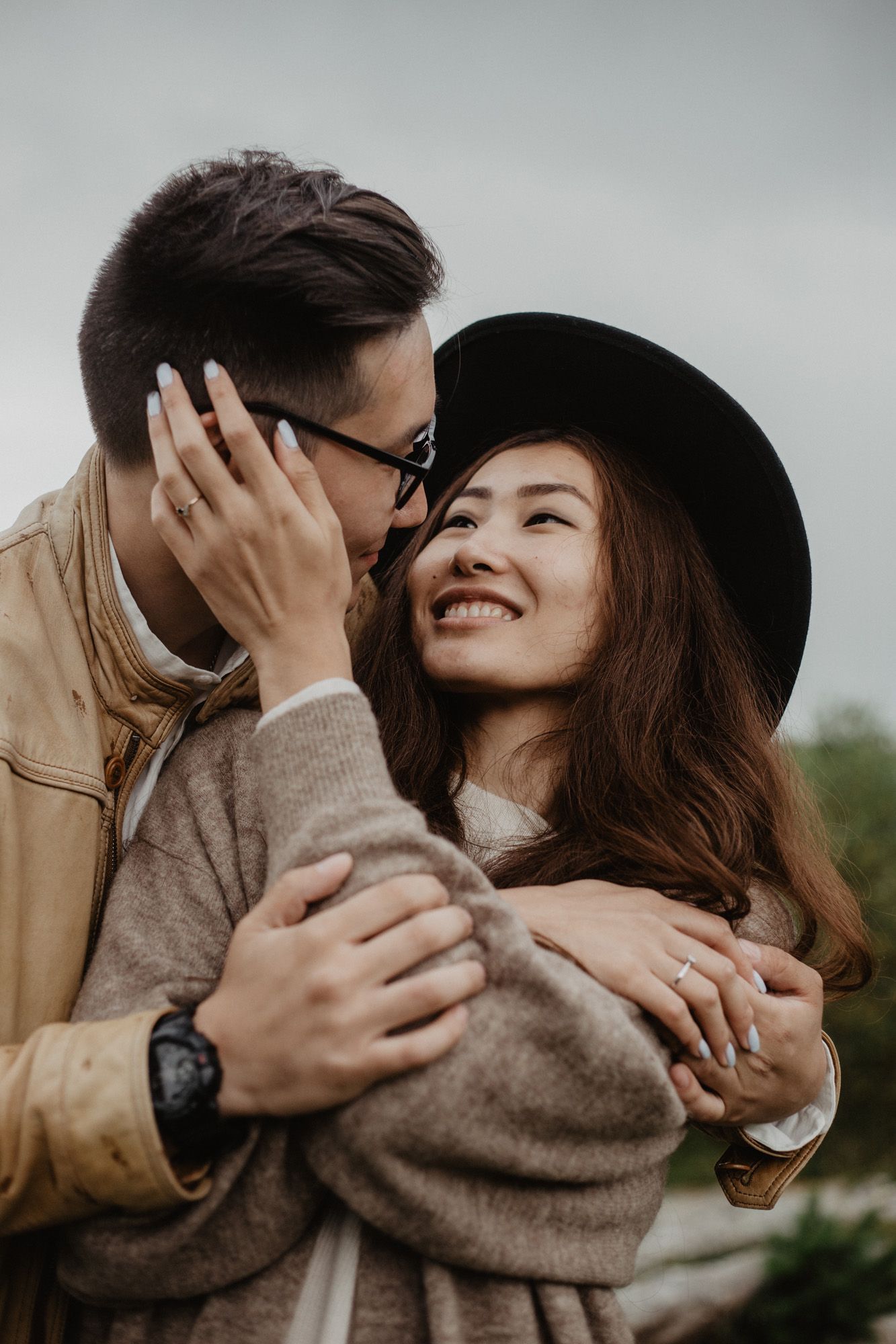 Intimate moment captured between couple in autumn outdoor setting wearing casual attire.
