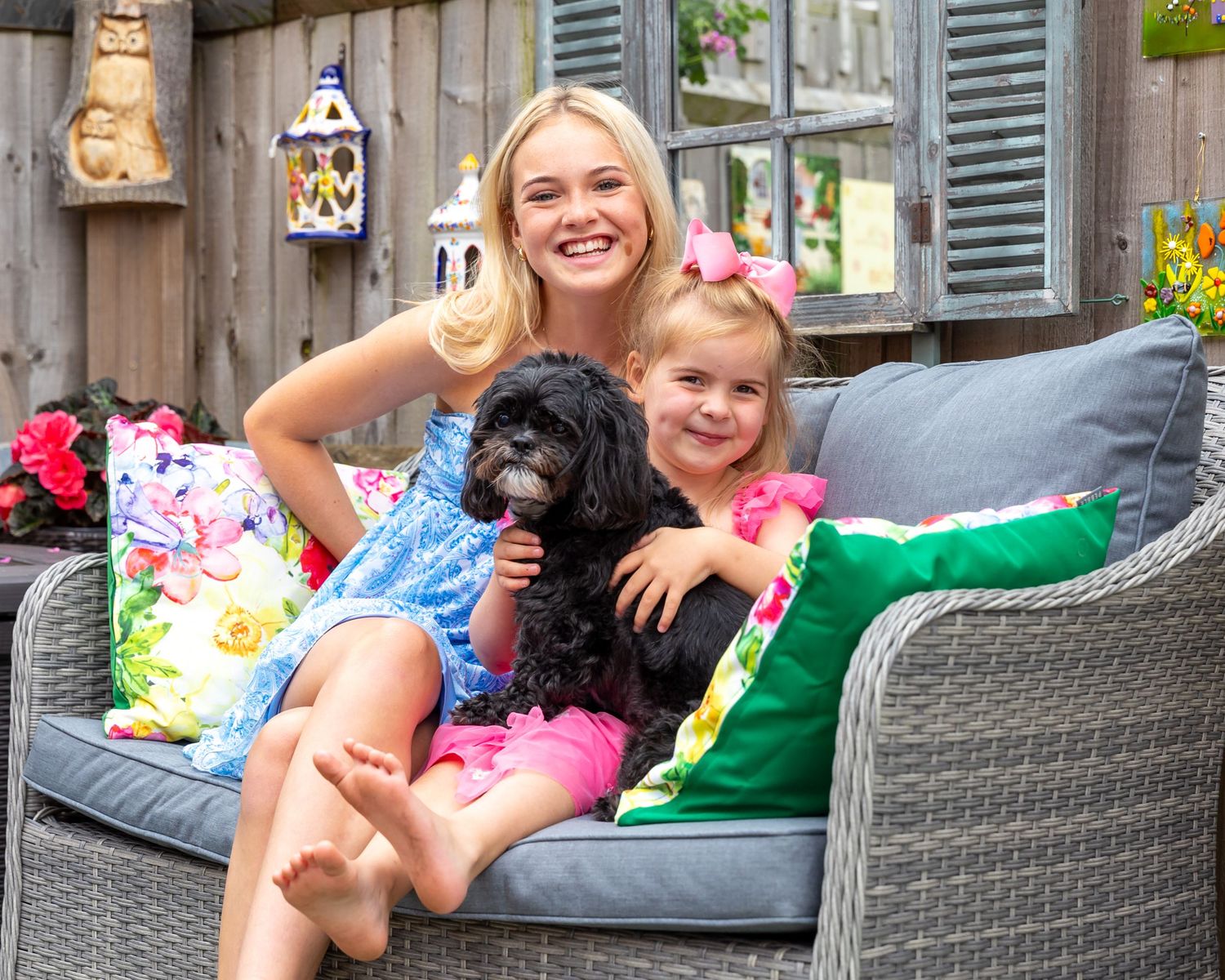 Happy family relaxing on outdoor patio furniture with decorative pillows.