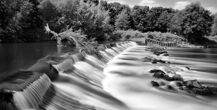Long exposure photograph of cascading waterfalls creating silky smooth water patterns in black and white.