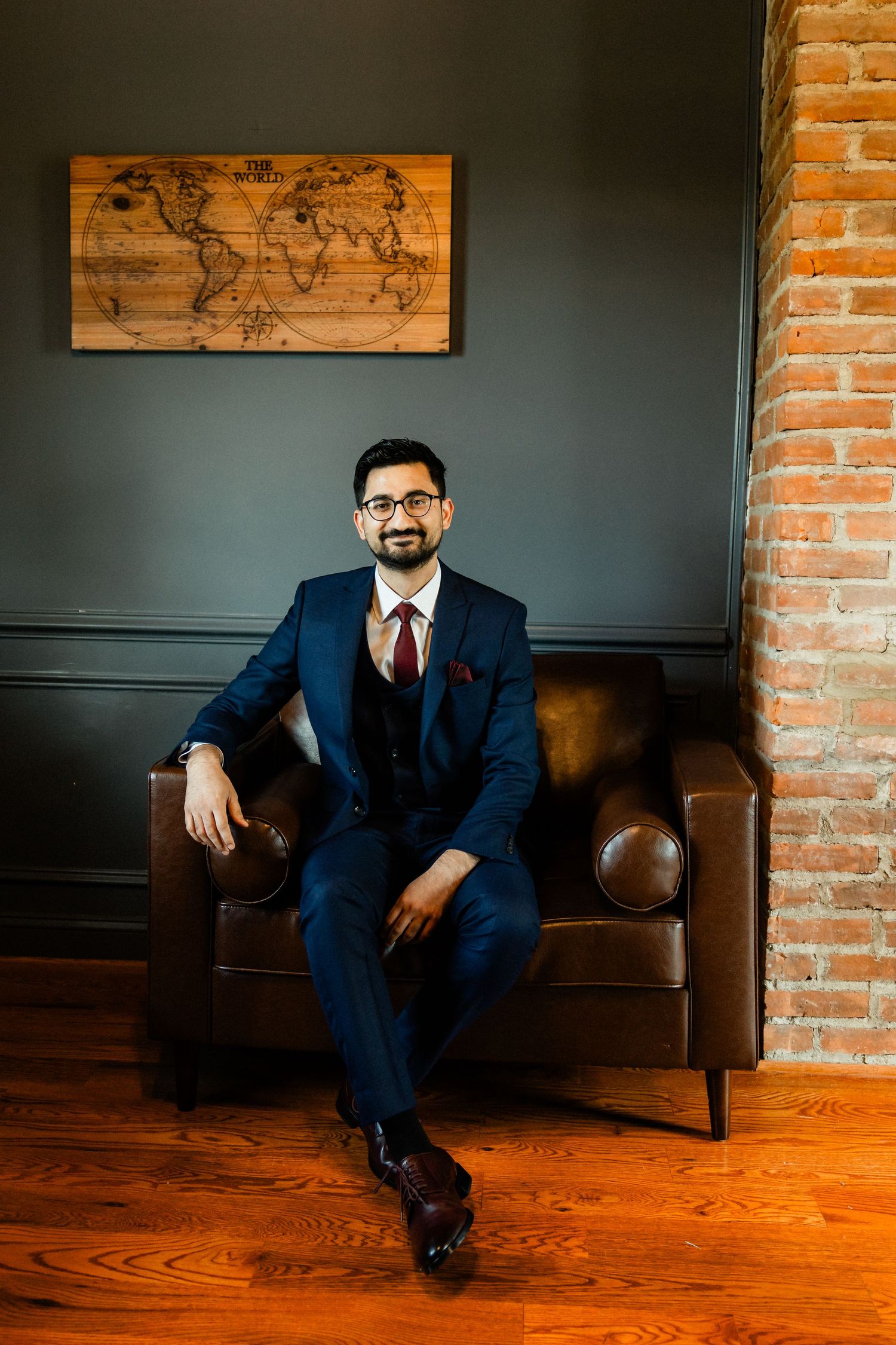 groom sitting in leather chair smiling at the camera