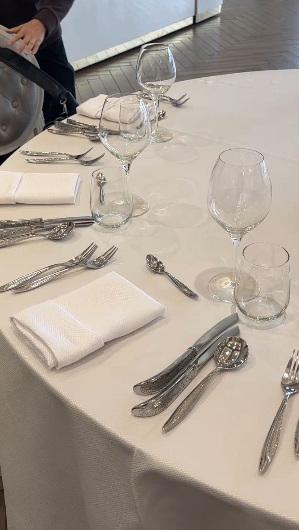 Elegant table setting with wine glasses, silverware, and white linens at an upscale restaurant.