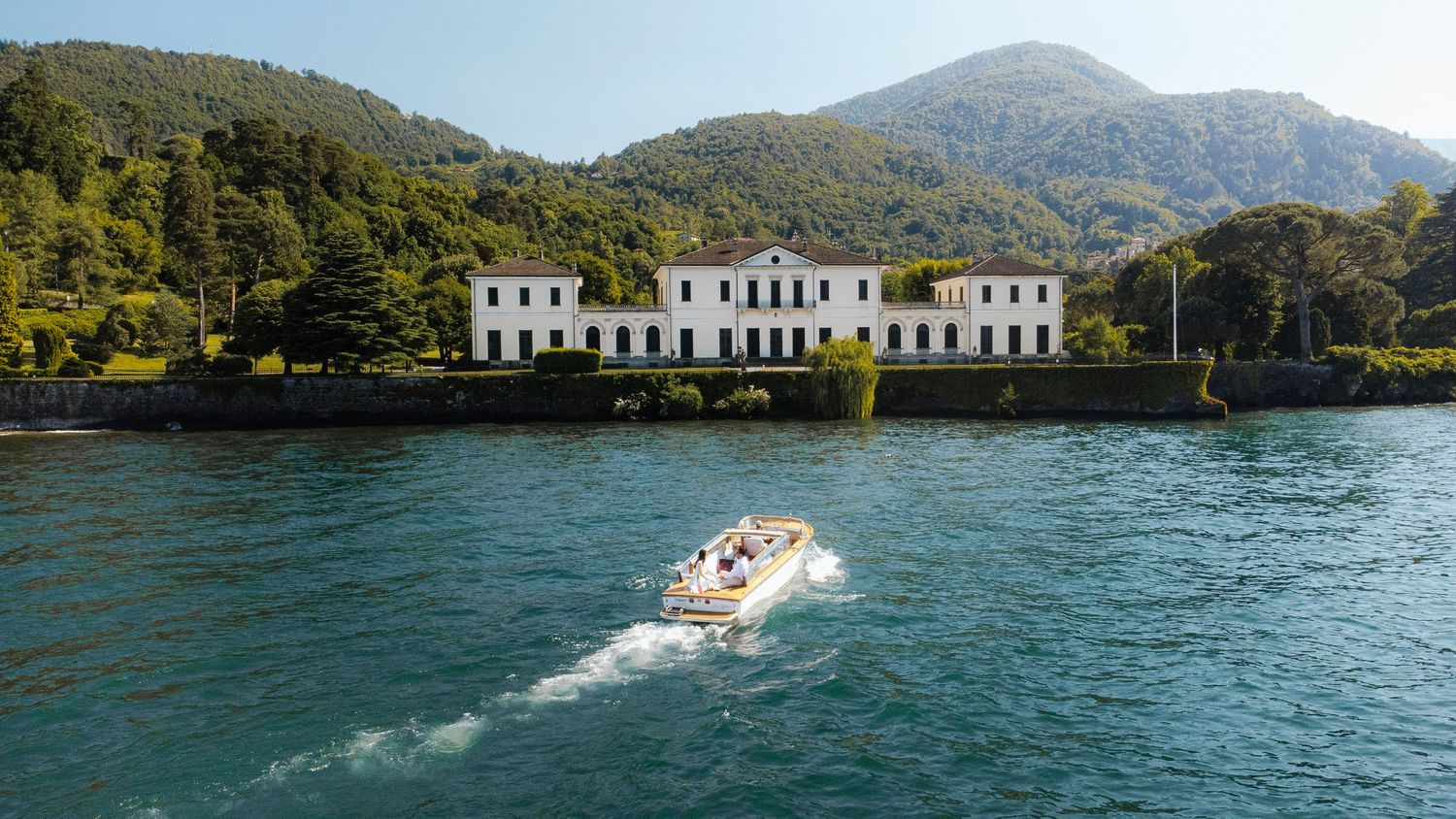 Mountain lakes and waterfront villas surrounded by lush green hills create a scenic panoramic view on Lake Como in Italy.