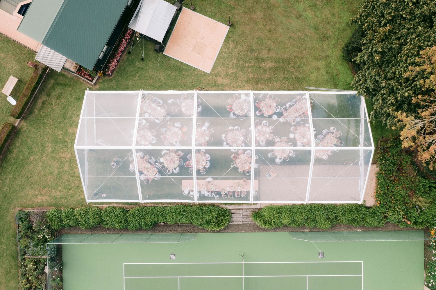 Aerial view of outdoor garden venue with green lawn and glass greenhouse structures.
