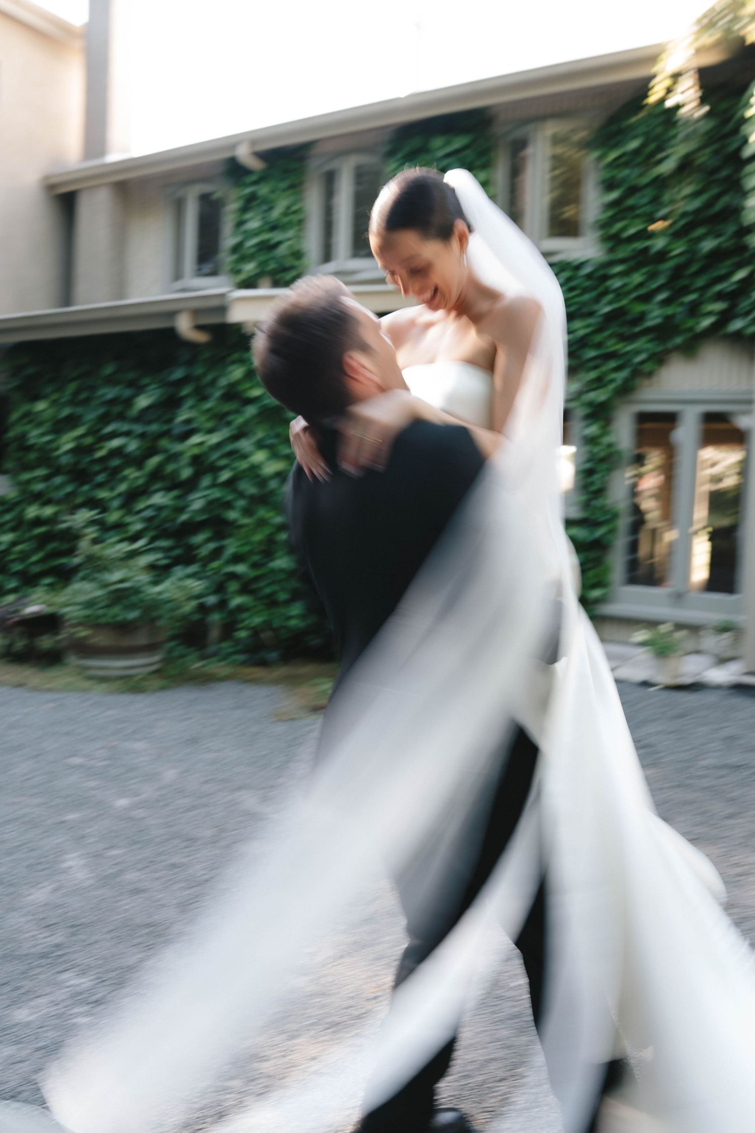 A joyful dance captured in motion blur against an ivy-covered building backdrop.